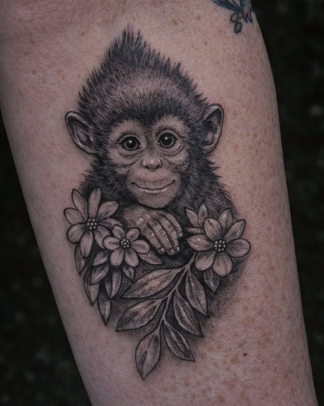 Baby monkey with flowers realism tattoo on the forearm by Marlayna Connelly