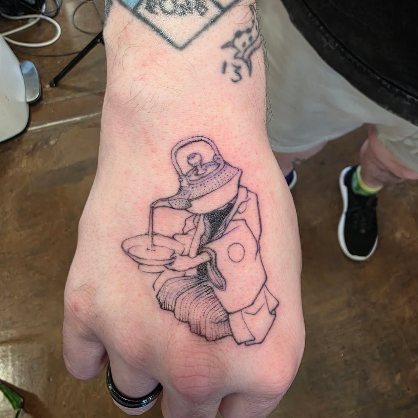 Teapot pouring tea black and grey tattoo on the hand by Keith Countryman, Fort Worth, Texas