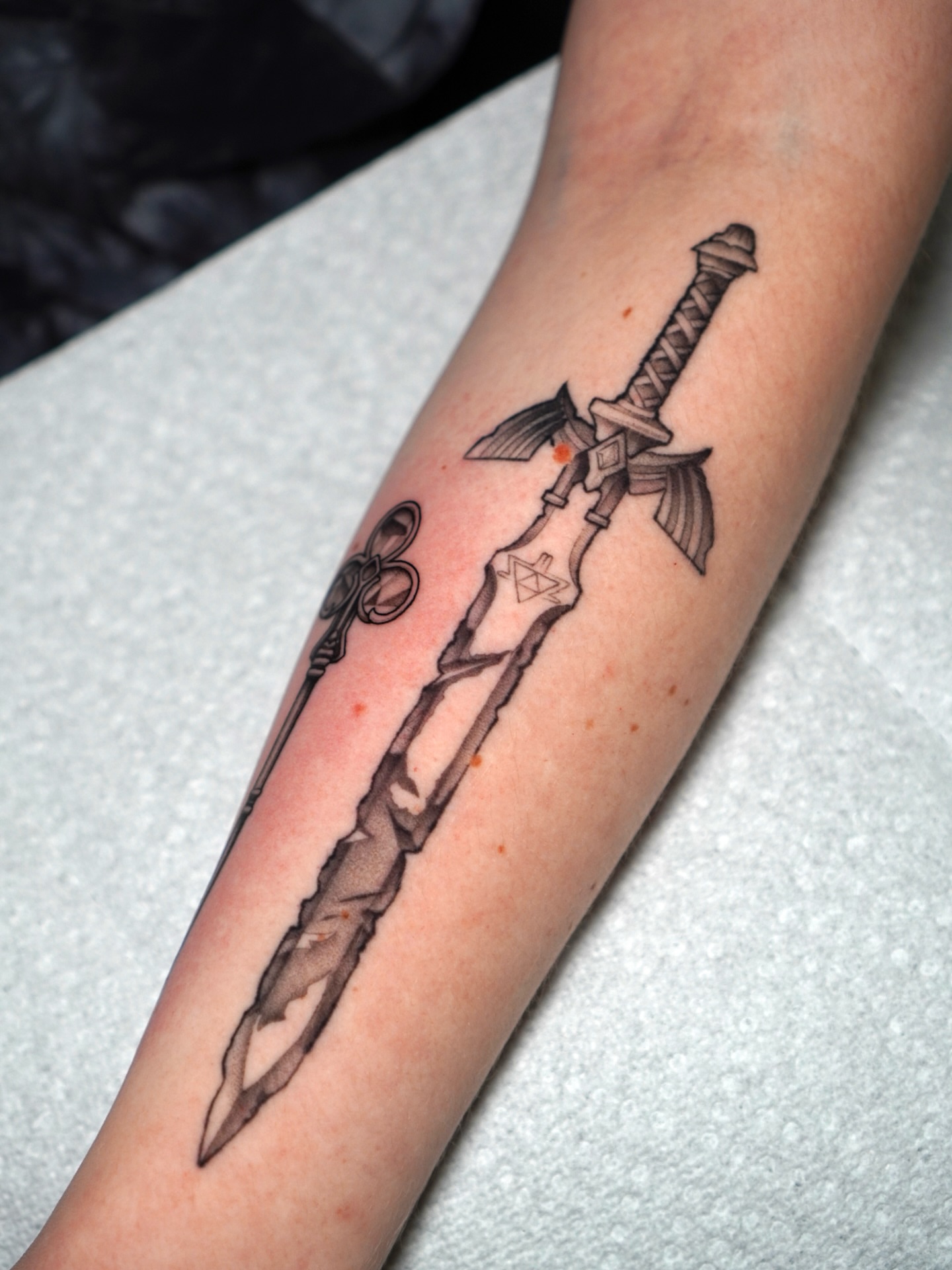 Sword black and grey tattoo on the forearm by Carlos Abad