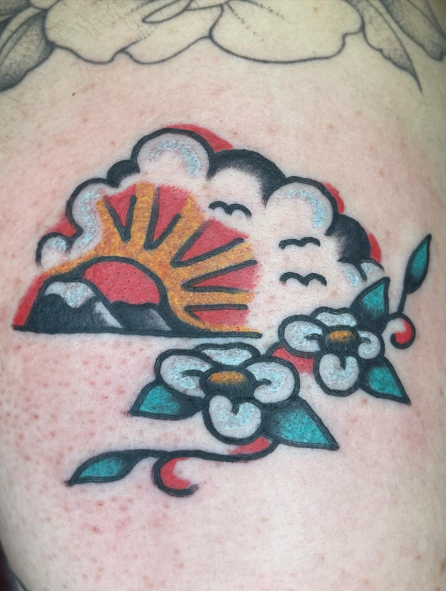 Sunrise with clouds and flowers American traditional tattoo on the shoulder by Nicholas M. Passeri