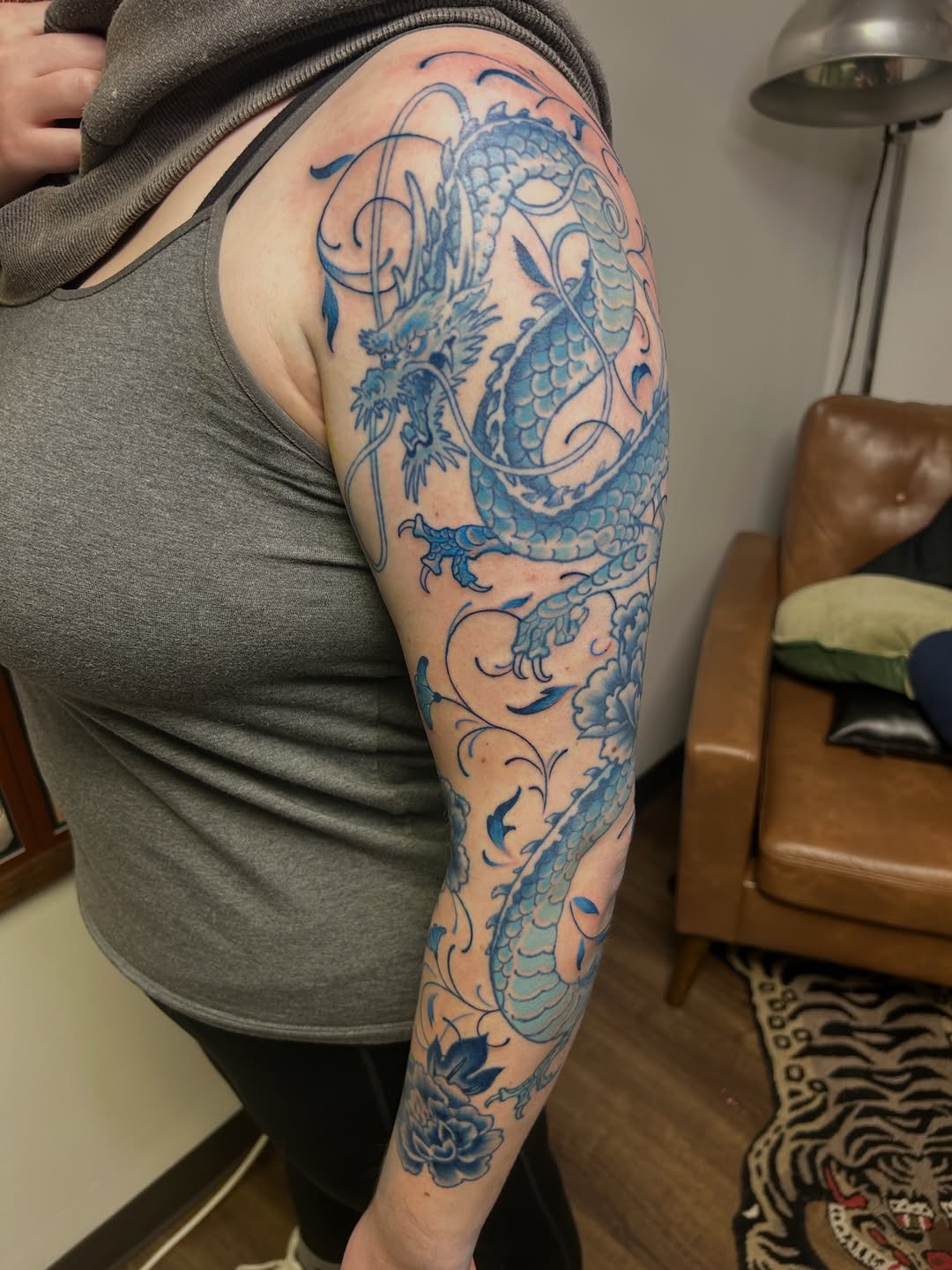 Dragon with floral elements watercolor tattoo on the upper arm by Dane Mitchell
