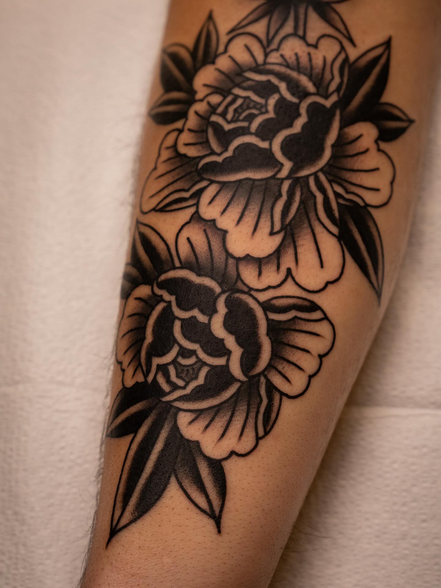 Peony flowers black and grey tattoo on the forearm by Justin Rakowski