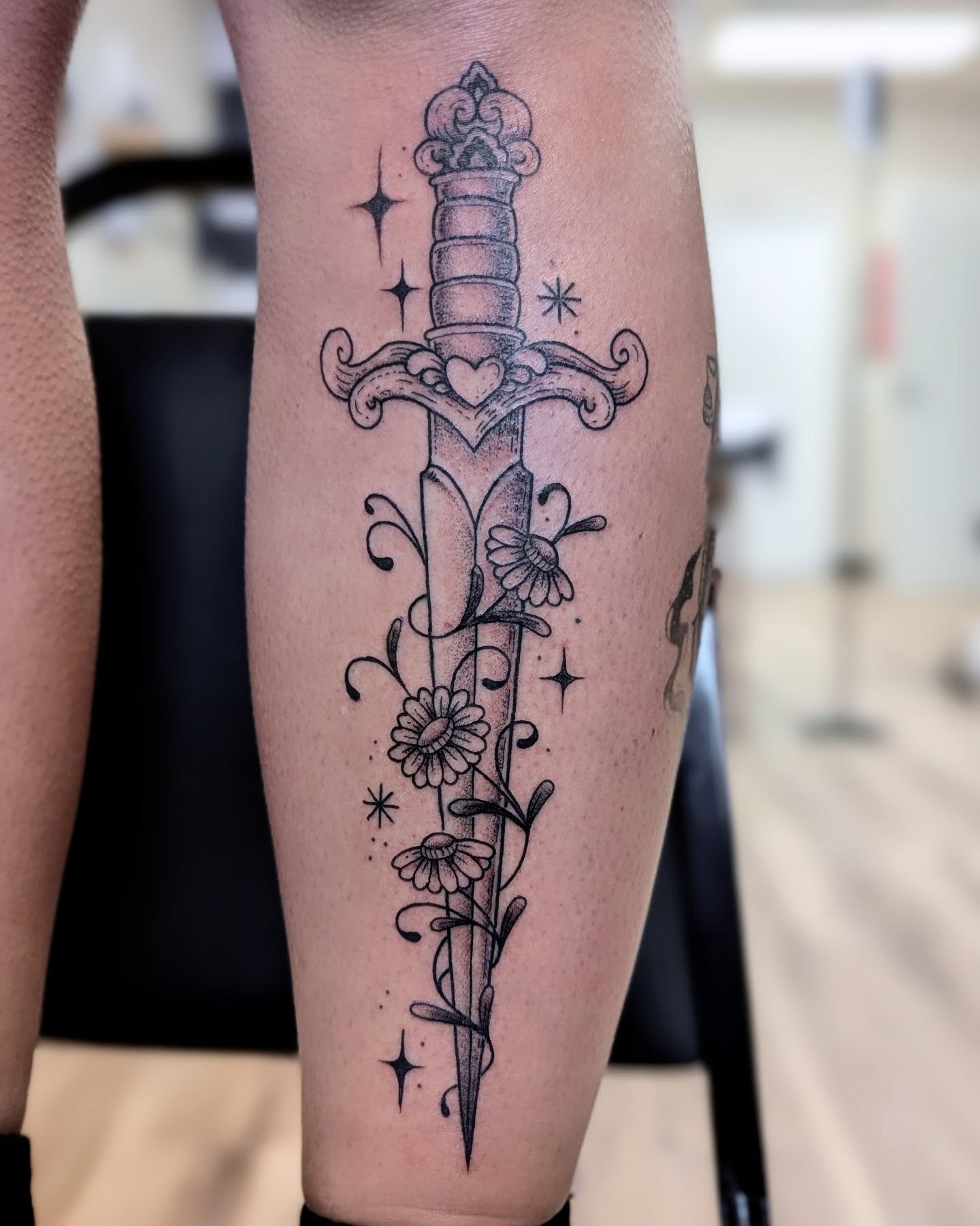 Sword with floral decoration black and grey tattoo on the forearm by Dani Harkey