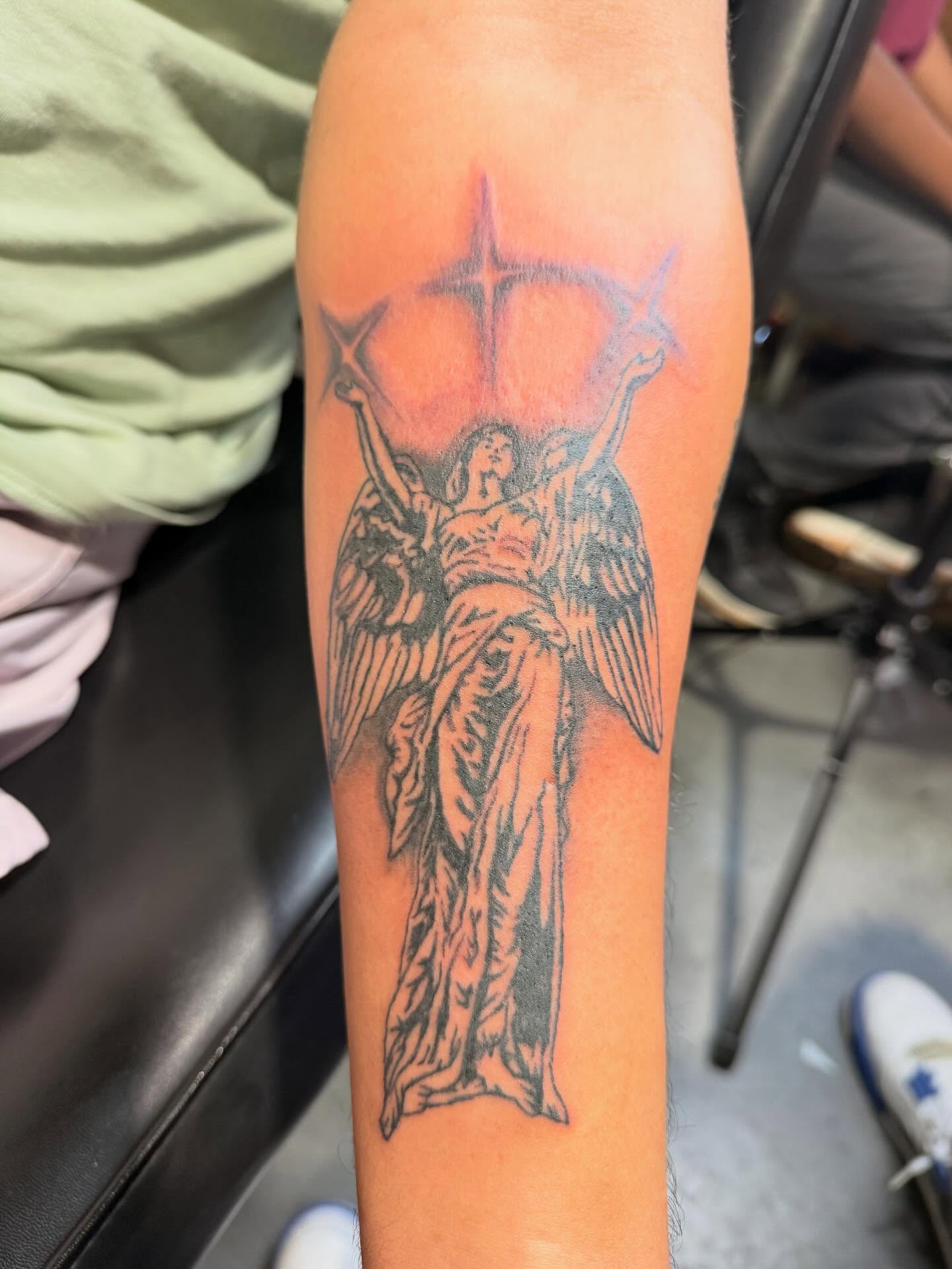 Angel with stars black and grey tattoo on the forearm by Jones Eric