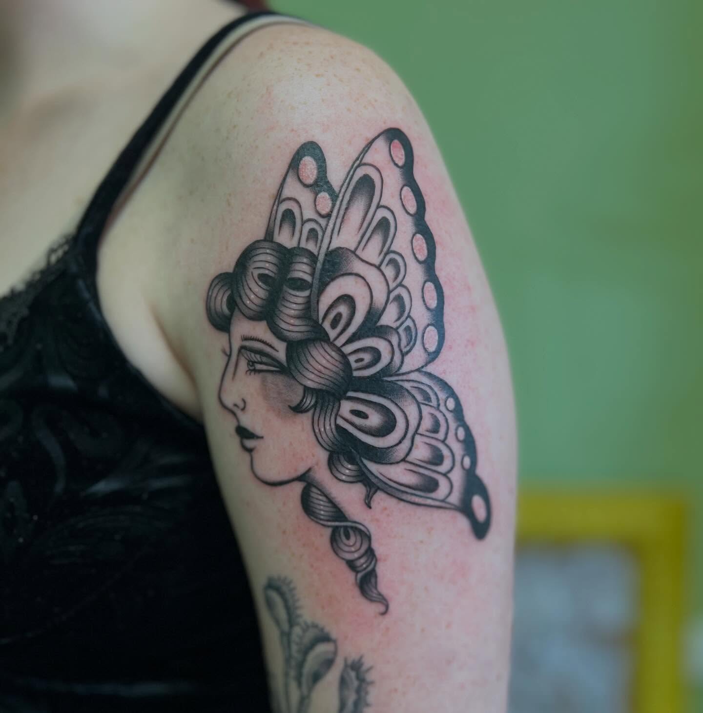 Woman with butterfly wings black and grey tattoo on the shoulder by charlie