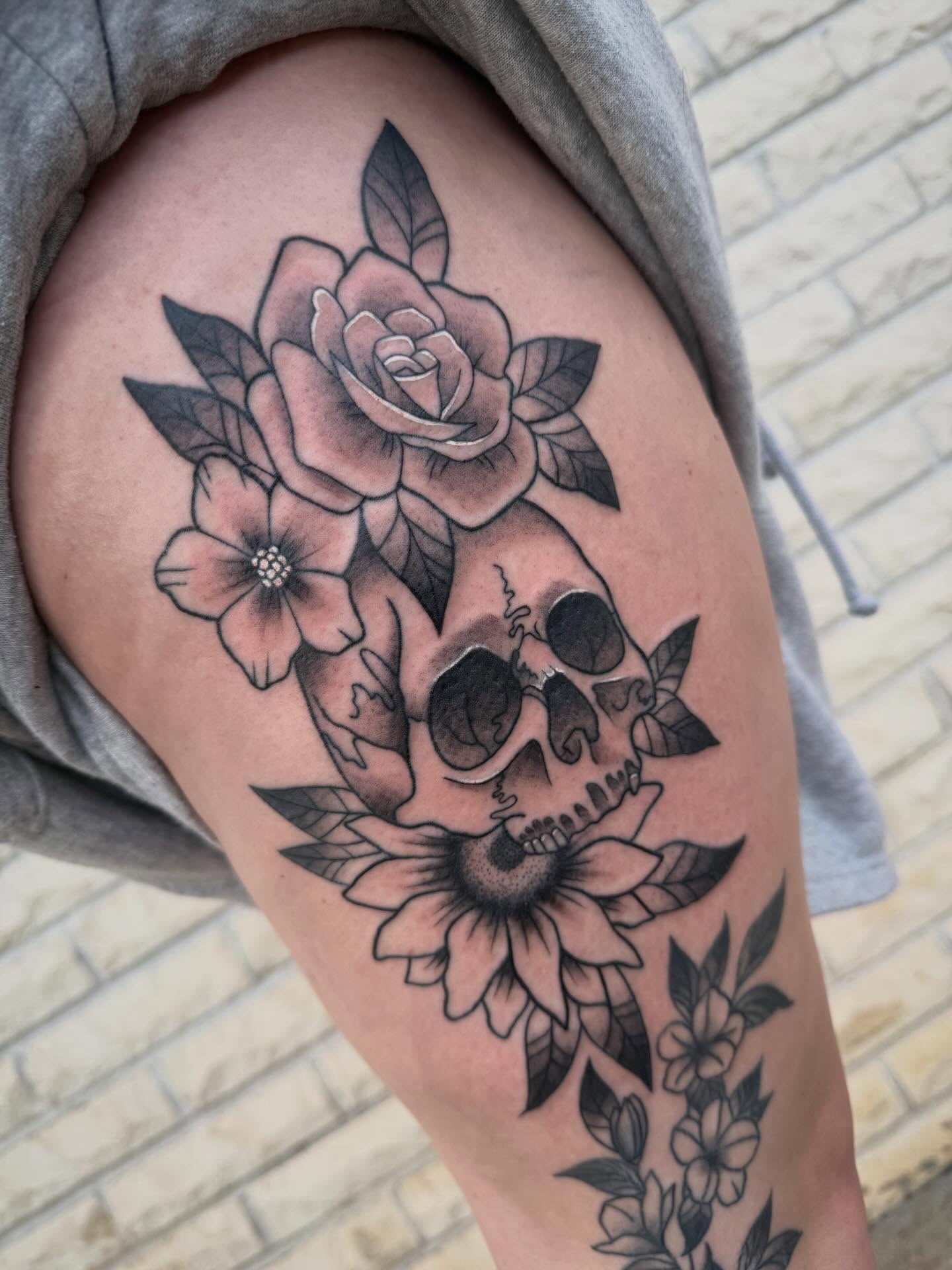 Skull and flowers American traditional tattoo on the thigh by Abby Hofman