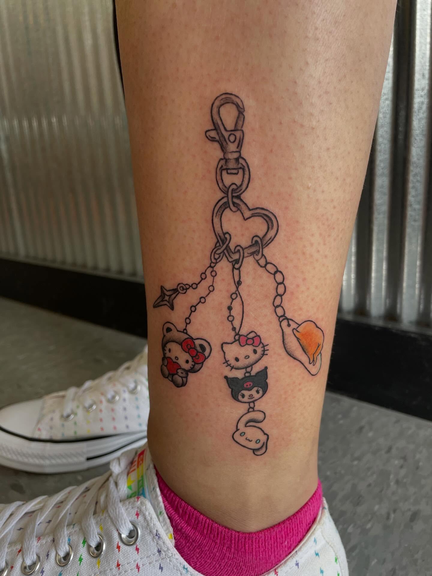 Hello Kitty charm bracelet dotwork tattoo on the calf by Mallory Moore