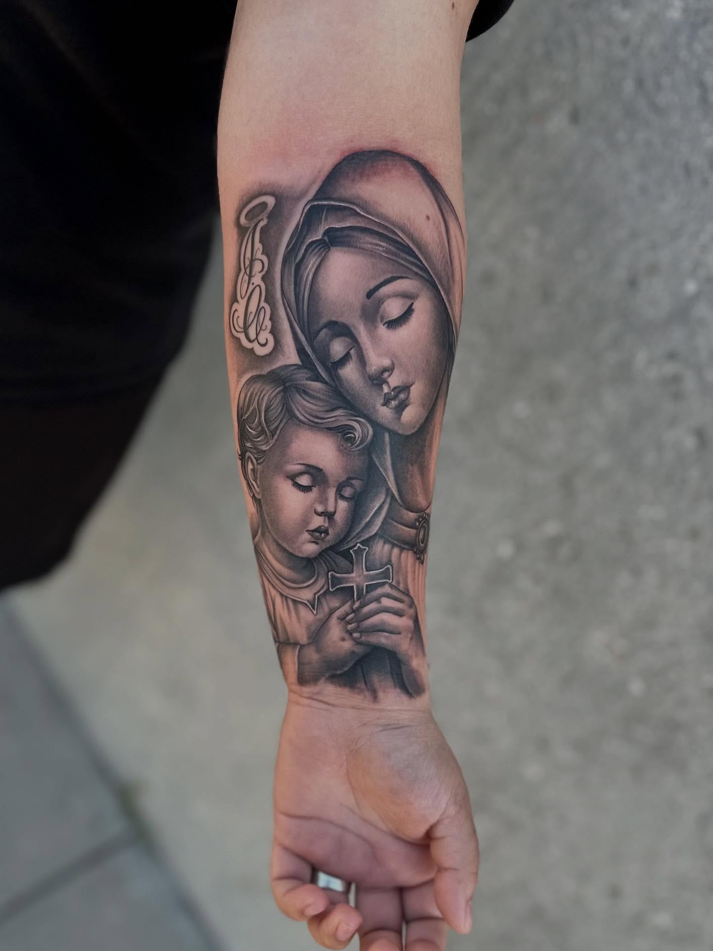 Religious figure and child realism tattoo on the forearm by Ruben