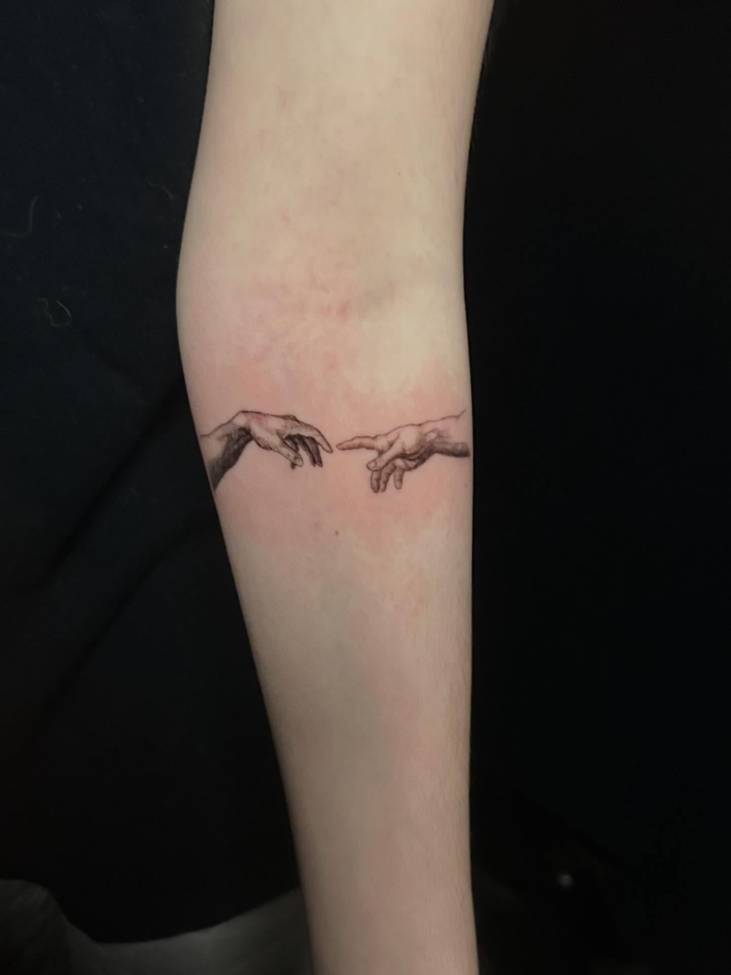 Touching hands black and grey tattoo on the forearm by Michigan Tattoo Artist - Emily Borneman