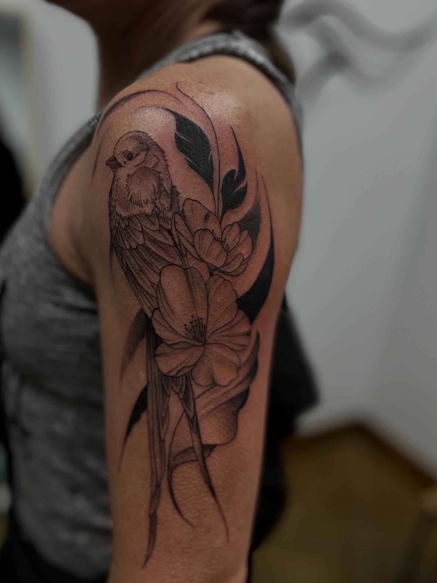 Bird and flowers realism tattoo on the upper arm by Rebecca Kern Tattoos