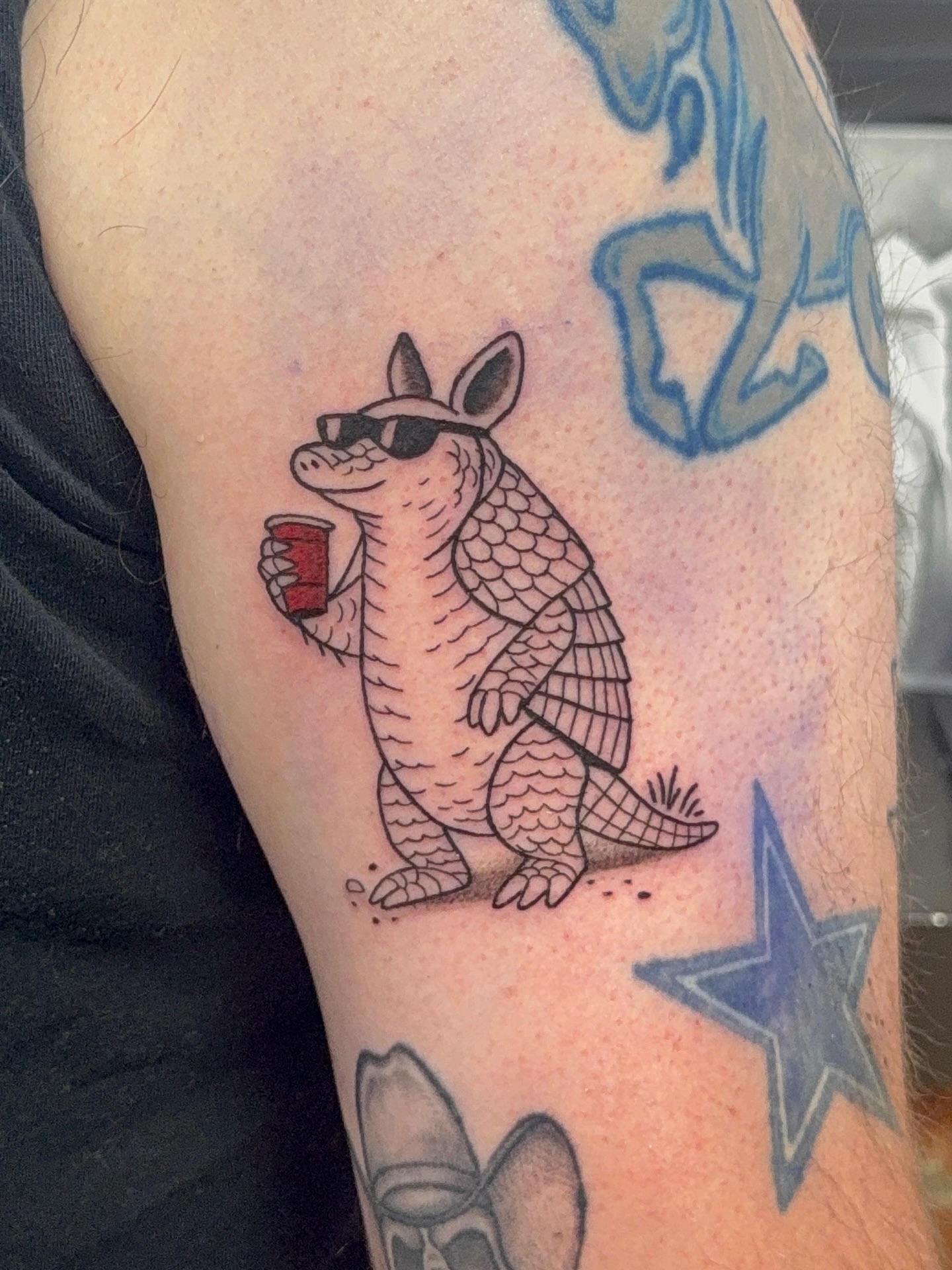 Armadillo drinking black and grey tattoo on the forearm by Royal Martinez