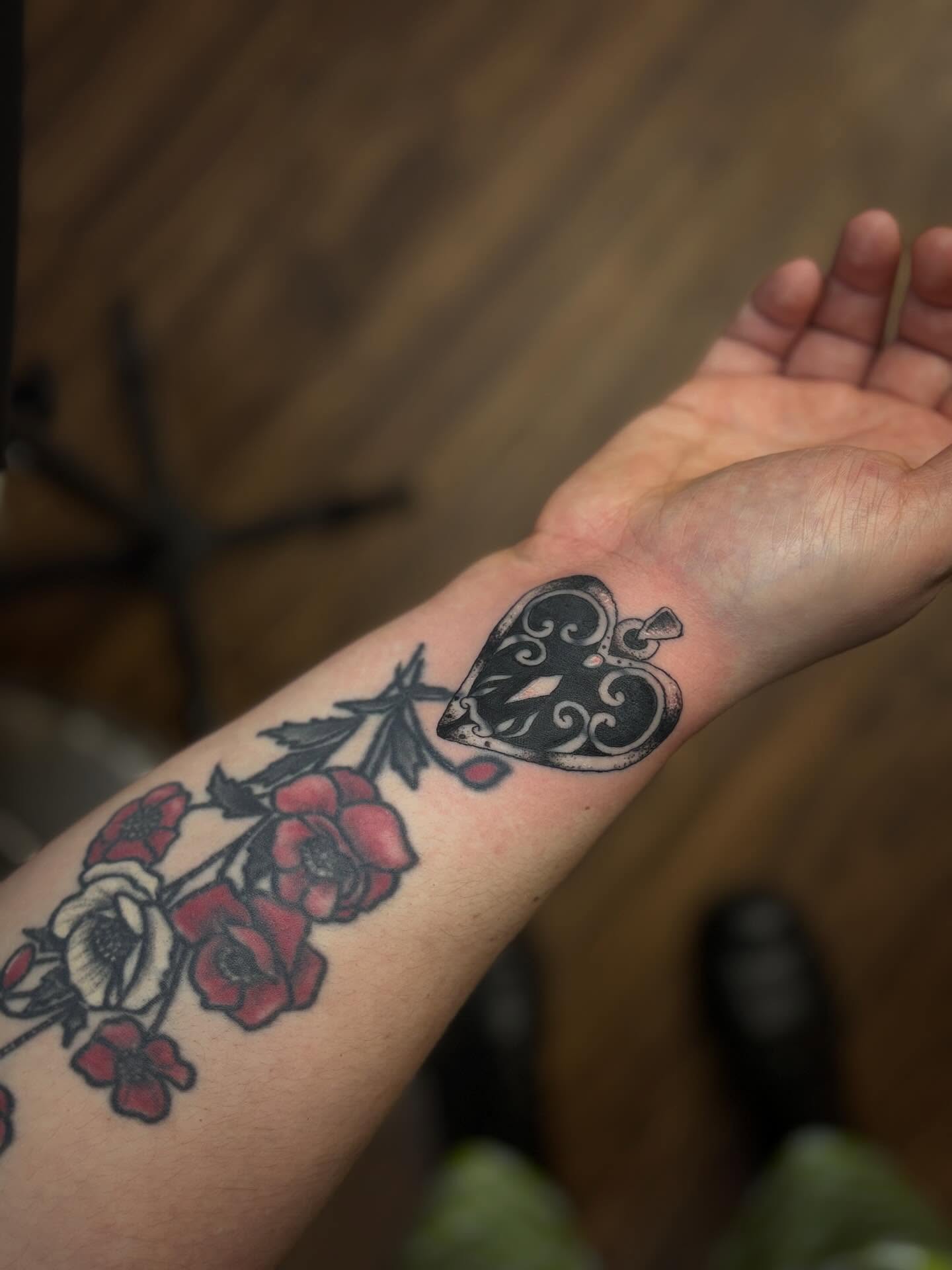 Mask and flowers American traditional tattoo on the forearm by Lauren Deets