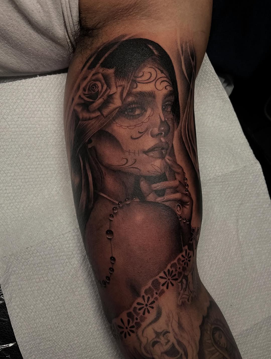 Woman with rose and rosary realism tattoo on the forearm by Denver Tattoo Artist