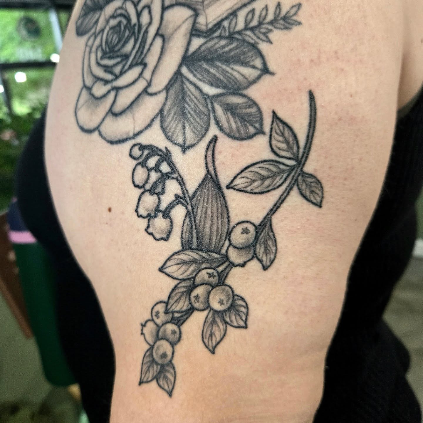Flower bouquet black and grey tattoo on the upper arm by Amanda Hinrichs