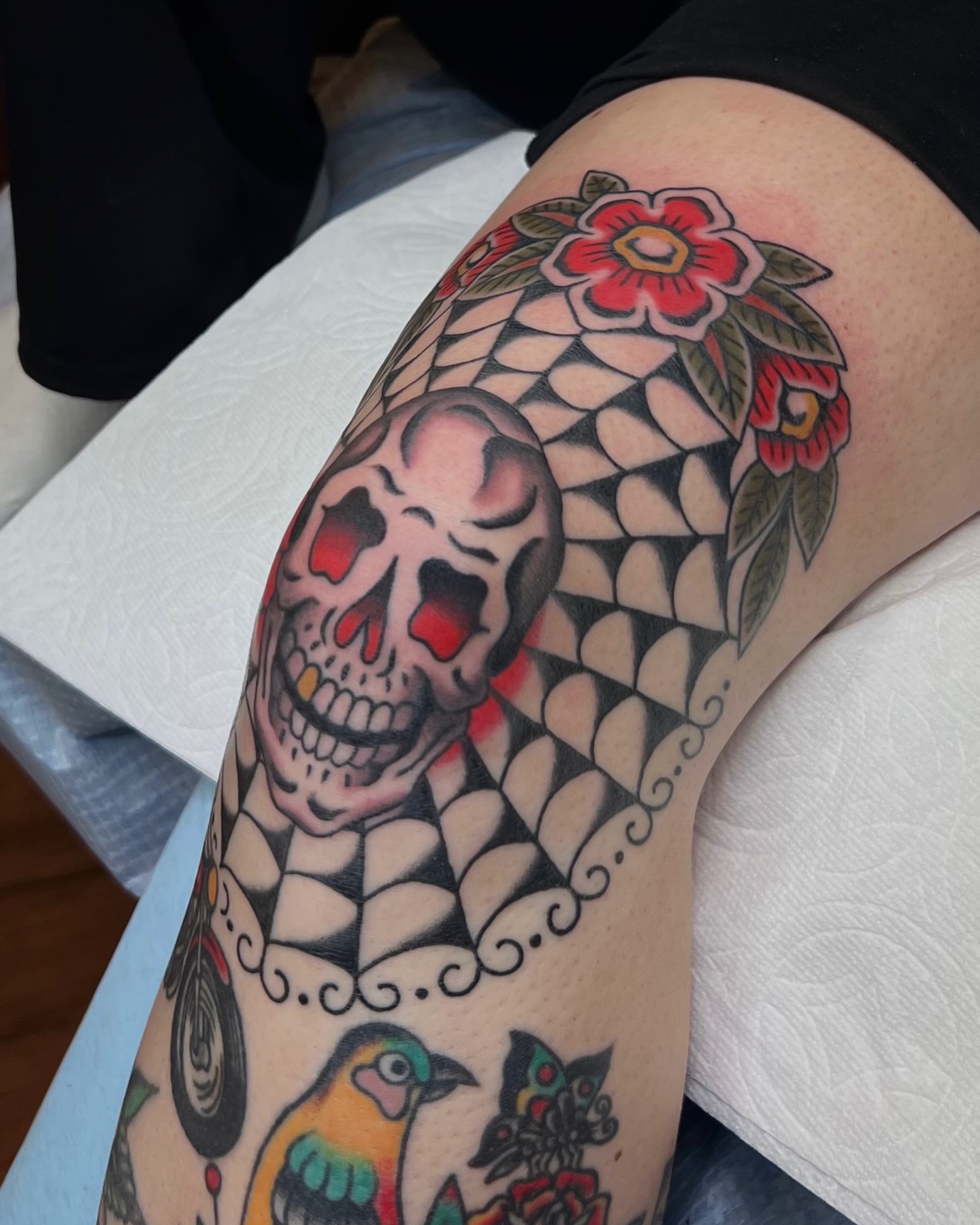 Skull and floral American traditional tattoo on the thigh by Brian Visser