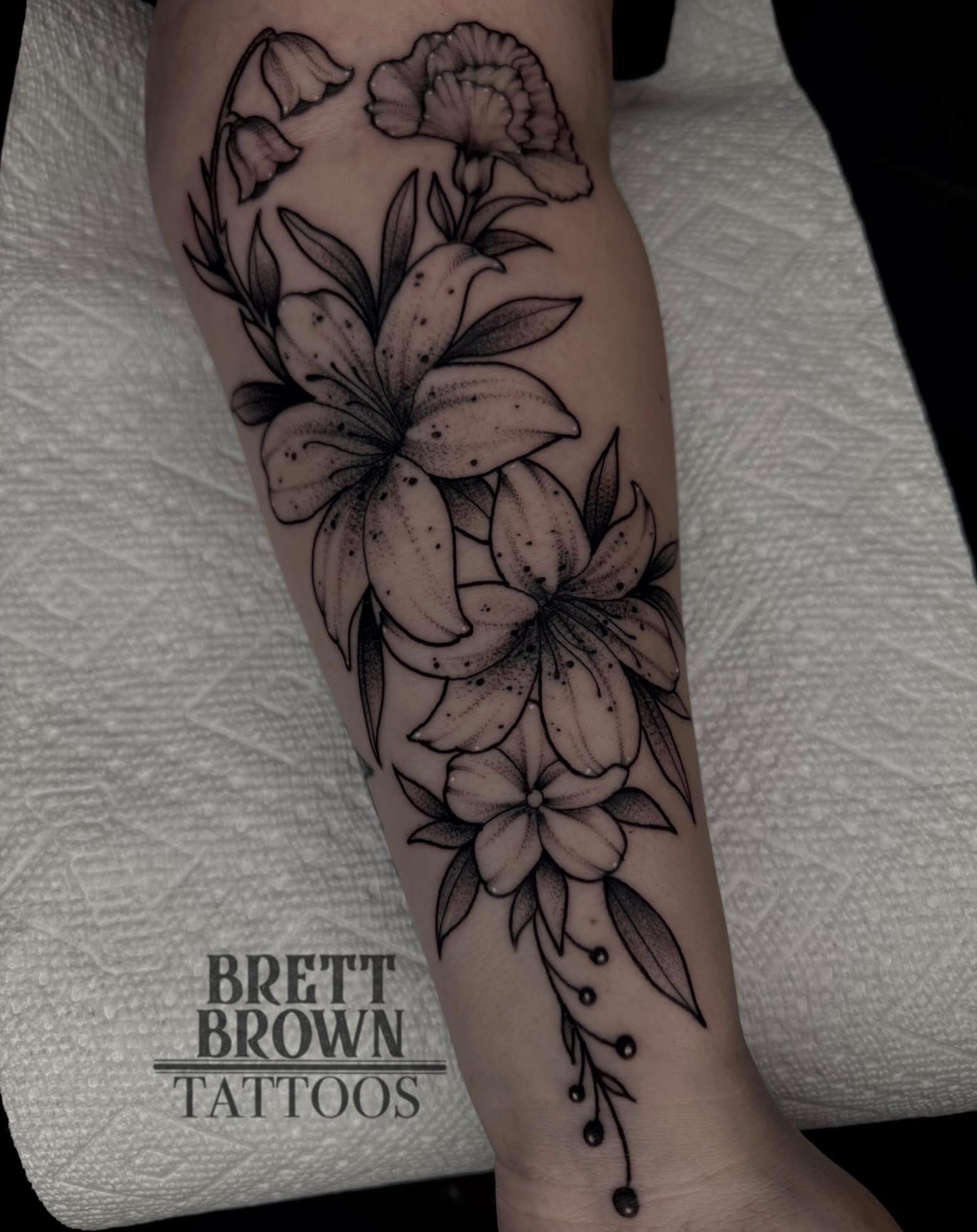 Lilies and leaves dotwork tattoo on the forearm by Brett Brown