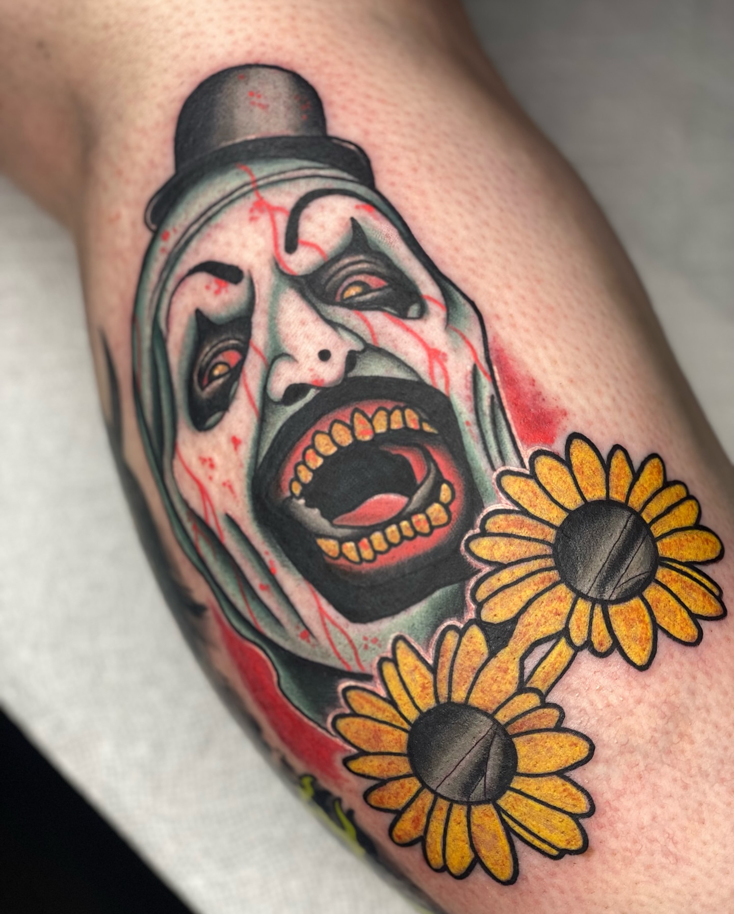 Clown face with flowers American traditional tattoo on the thigh by Sideshow Danny