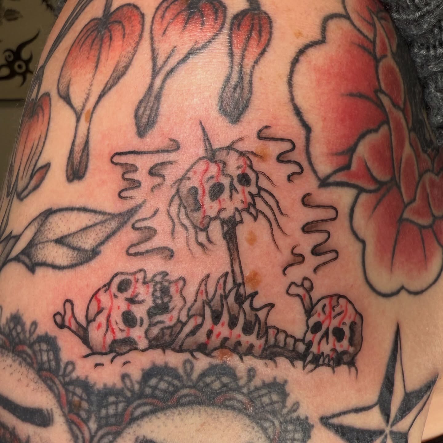 Skulls and flowers American traditional tattoo on the upper arm by Kaysen