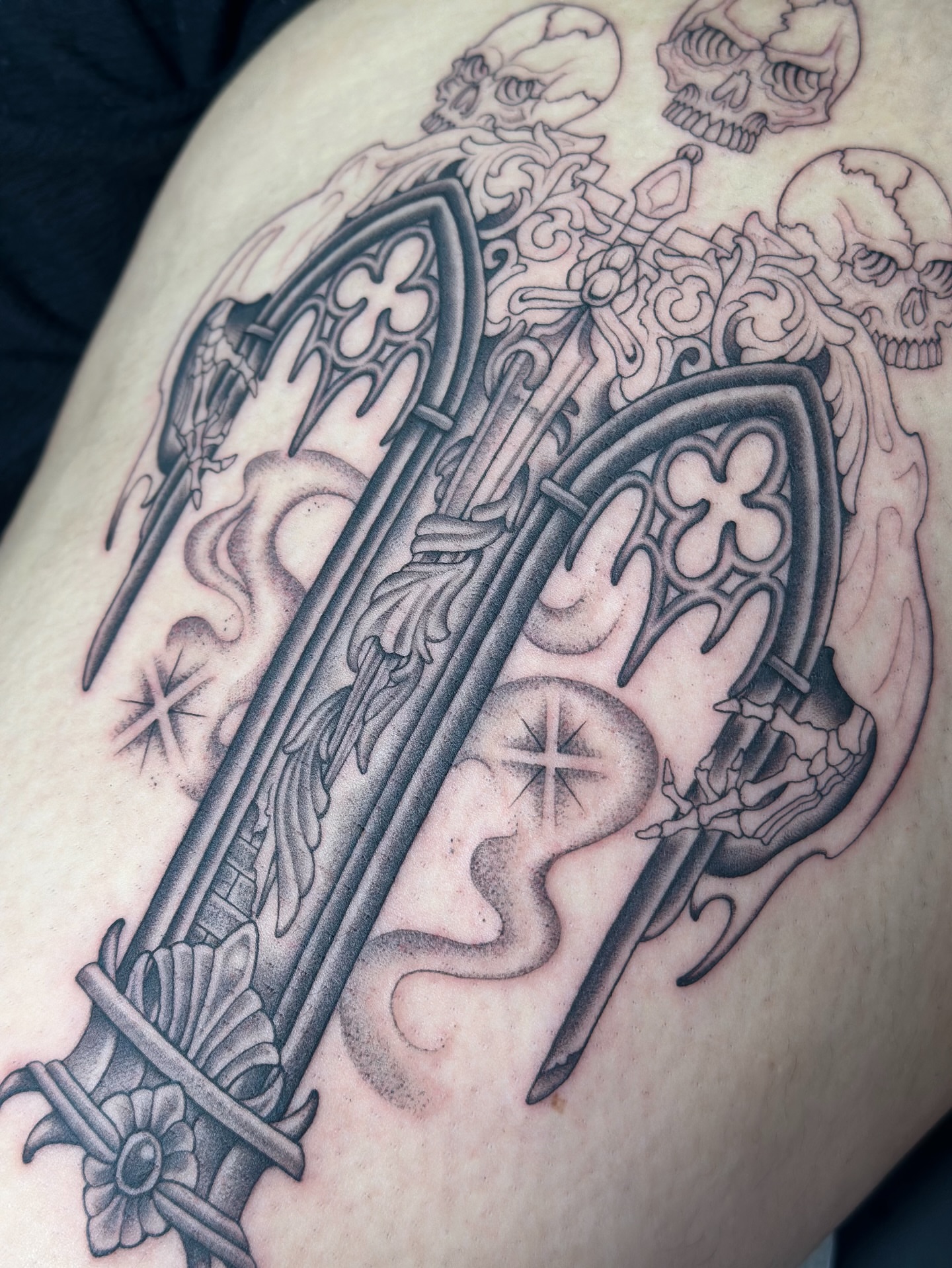 Cross and skulls black and grey tattoo on the thigh by Lauryn Jenesis