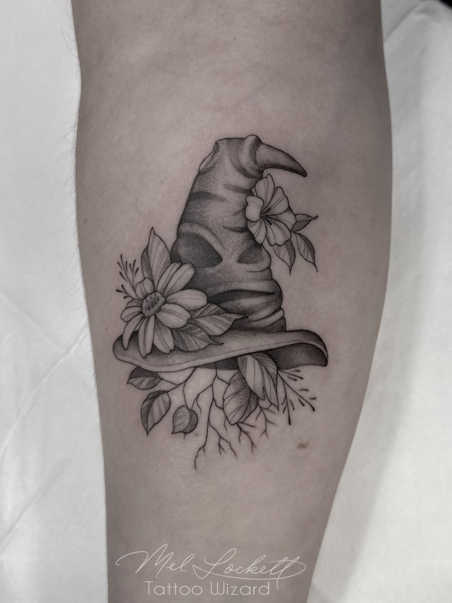 Wizard hat and flowers black and grey tattoo on the forearm by Mel K Lockett - Nashville Tattoo Artist