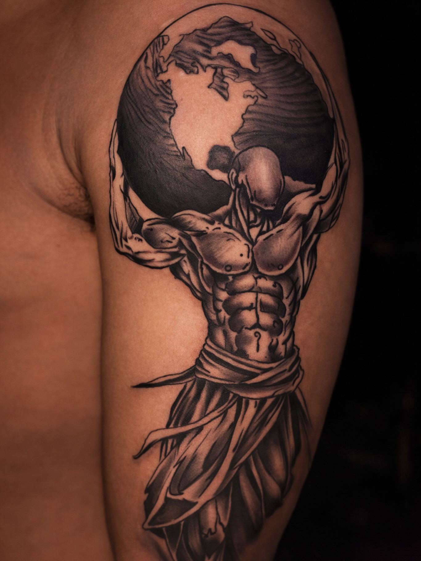 Muscular man holding globe realism tattoo on the upper arm by Shane Boss, Toronto, Ontario
