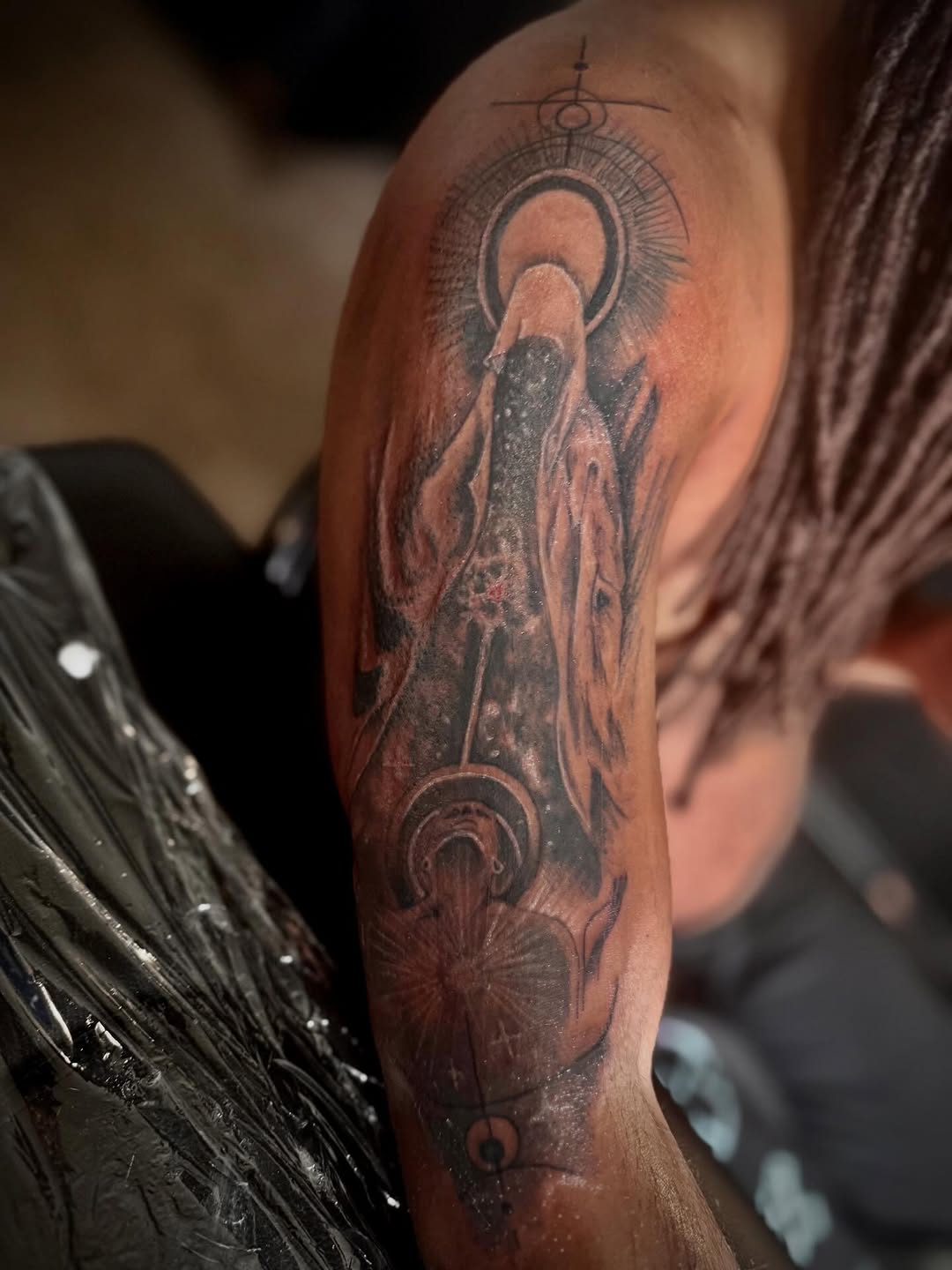 Figure with celestial elements realism tattoo on the upper arm by Eunoia Tattoos