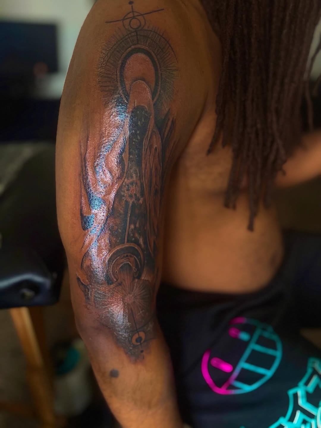 Figure with halo and geometric elements realism tattoo on the shoulder by Eunoia Tattoos