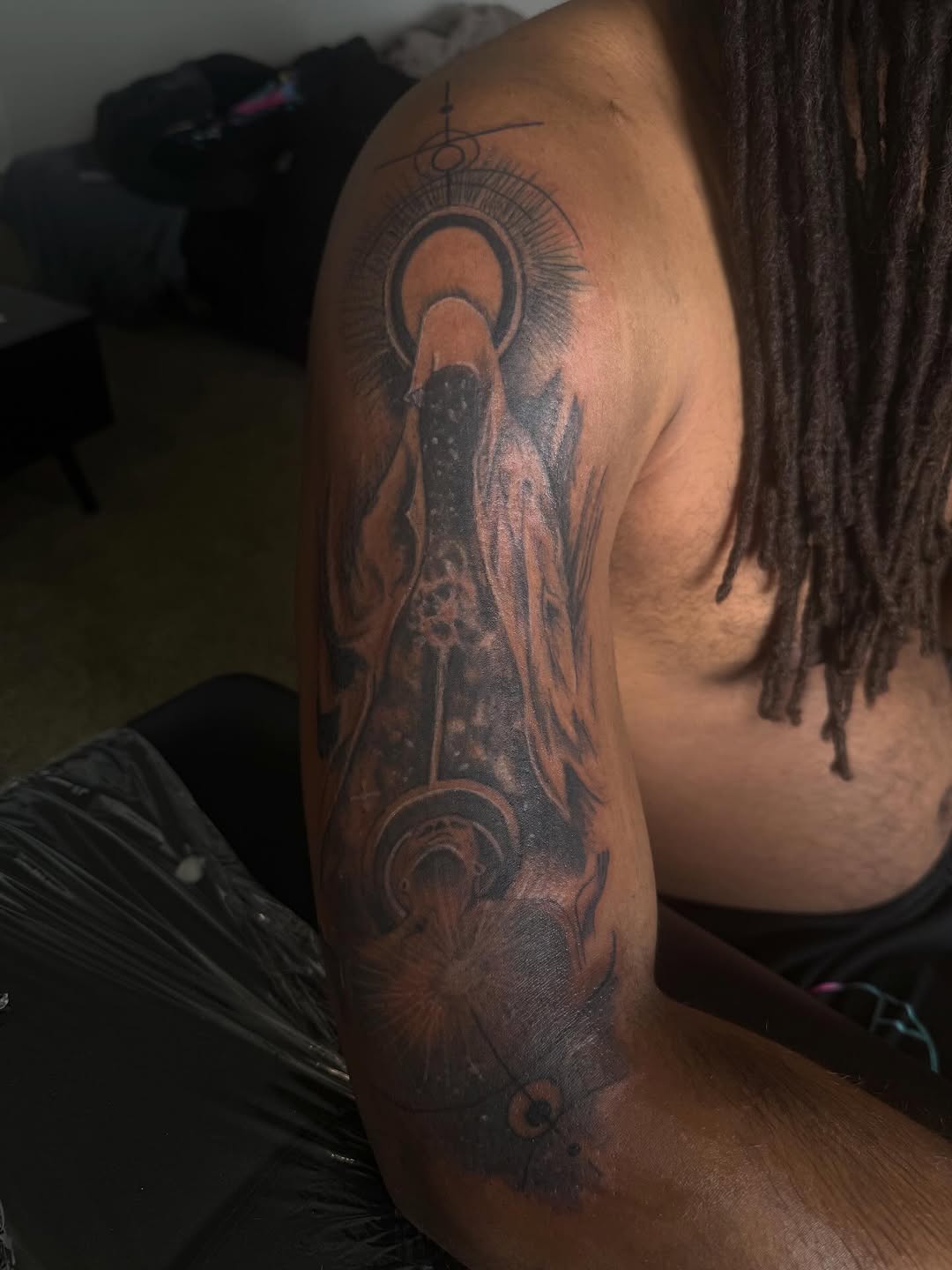Figure with halo and geometric elements realism tattoo on the shoulder by Eunoia Tattoos