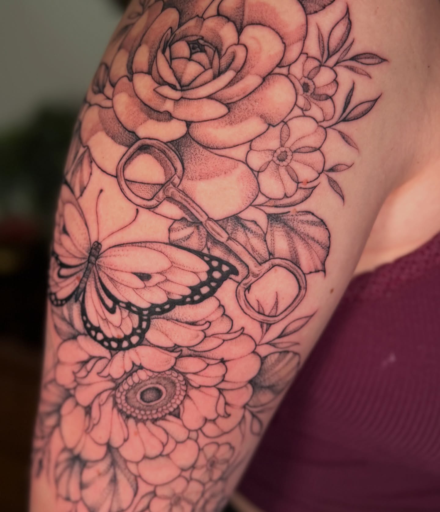 Flowers and butterfly black and grey tattoo on the upper arm by Chiah