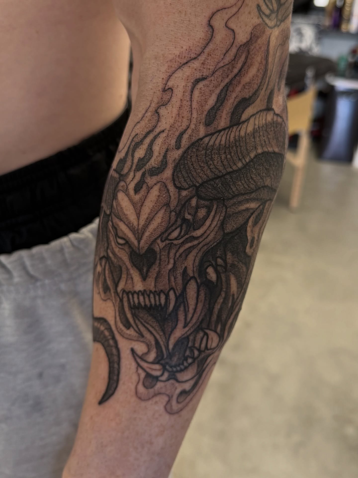 Demon skull black and grey tattoo on the forearm by Christopher Layman