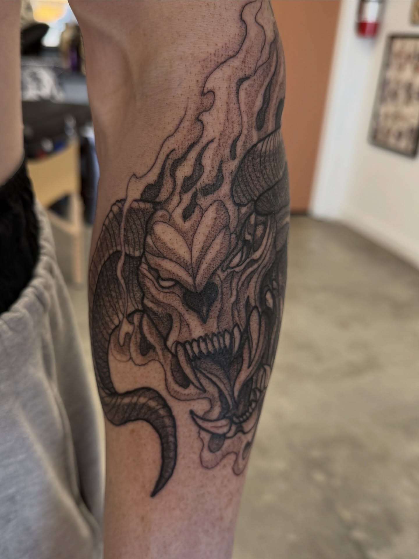 Demon skull black and grey tattoo on the forearm by Christopher Layman