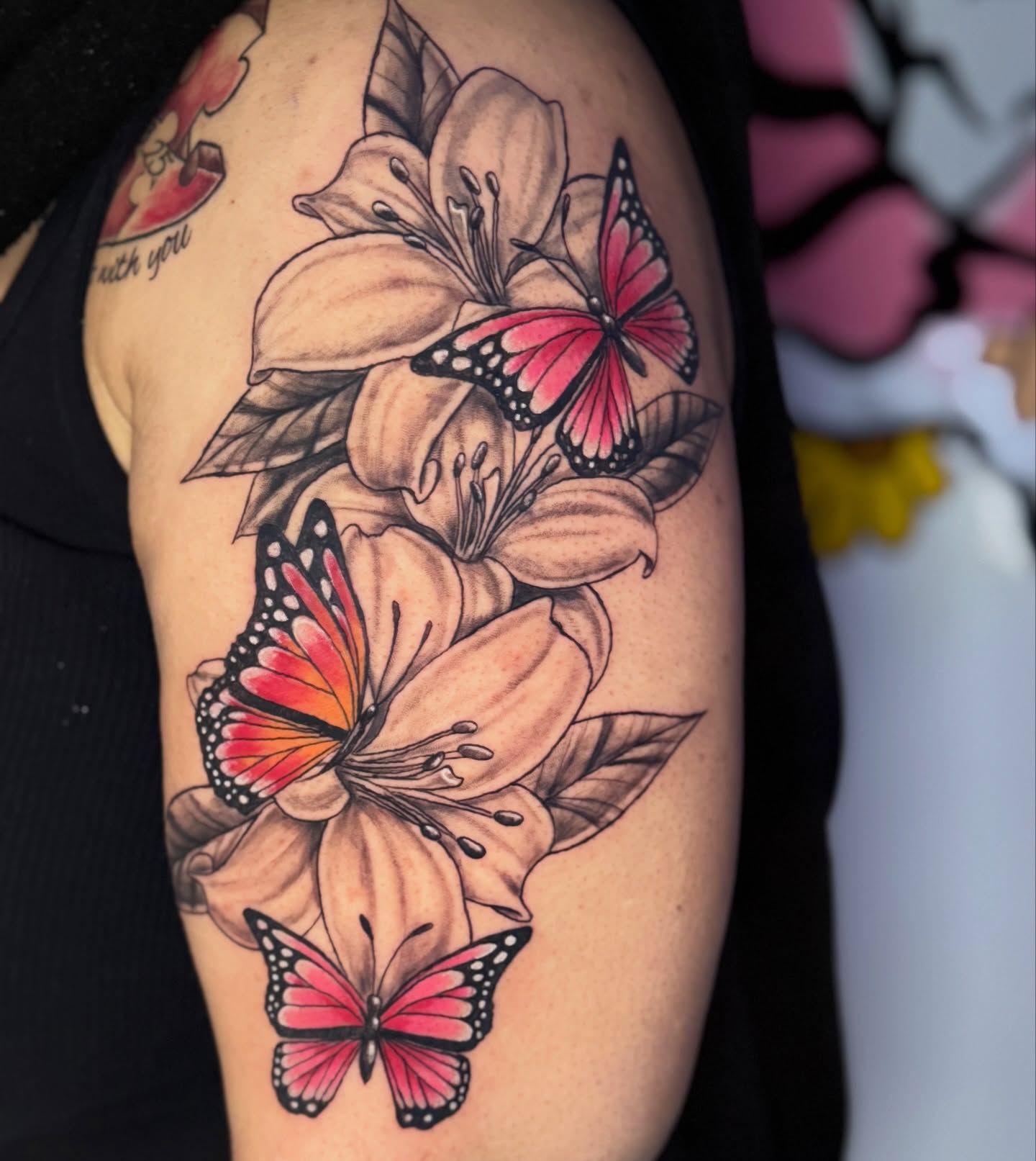 Lilies and butterflies realism tattoo on the upper arm by claud, Atlanta, Georgia