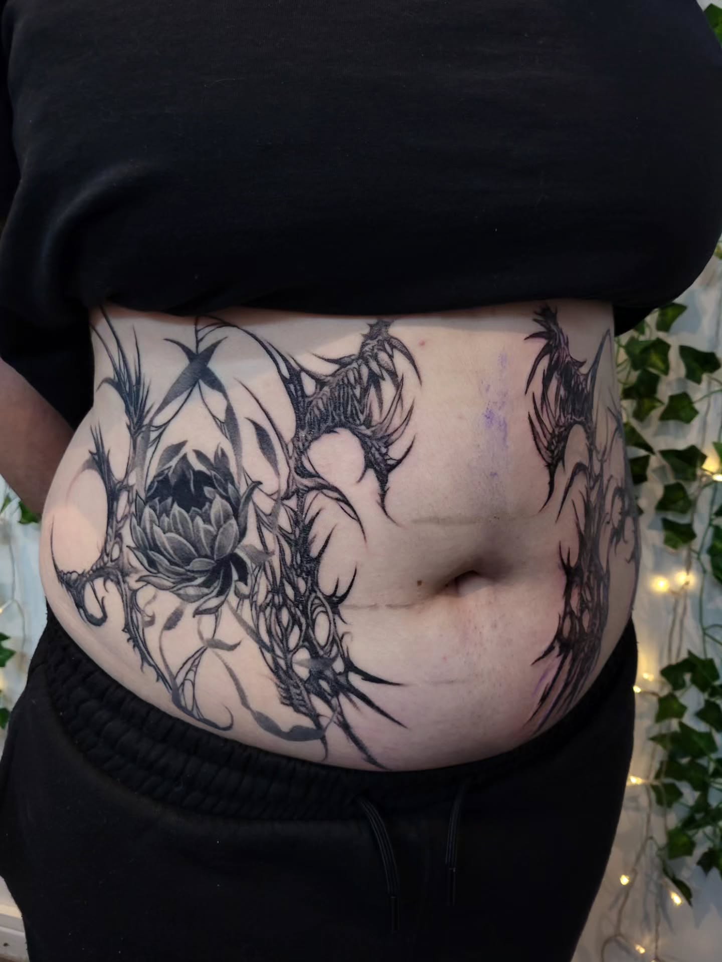 Thorned flower black and grey tattoo on the torso by Uku Tattoos, Cambridge, England