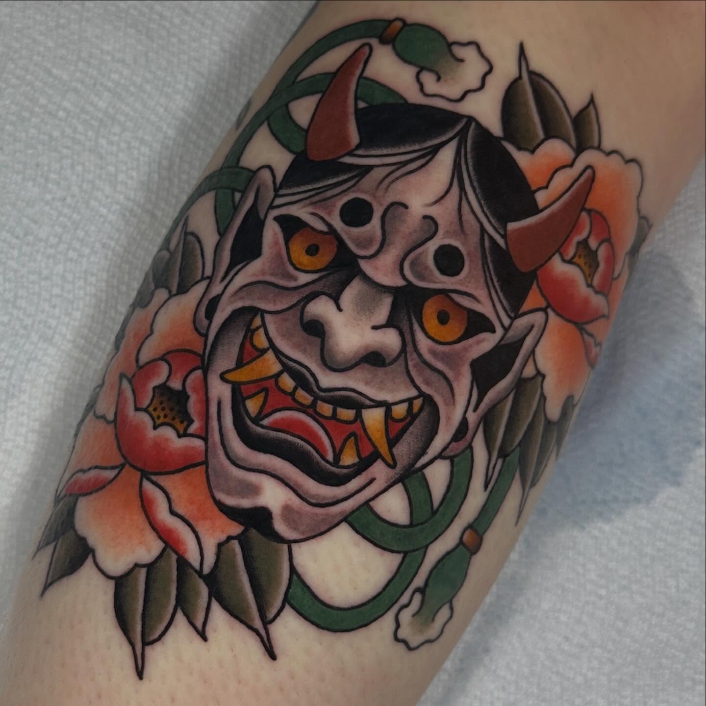 Demon mask with flowers American traditional tattoo on the forearm by Kyle Logan Frary