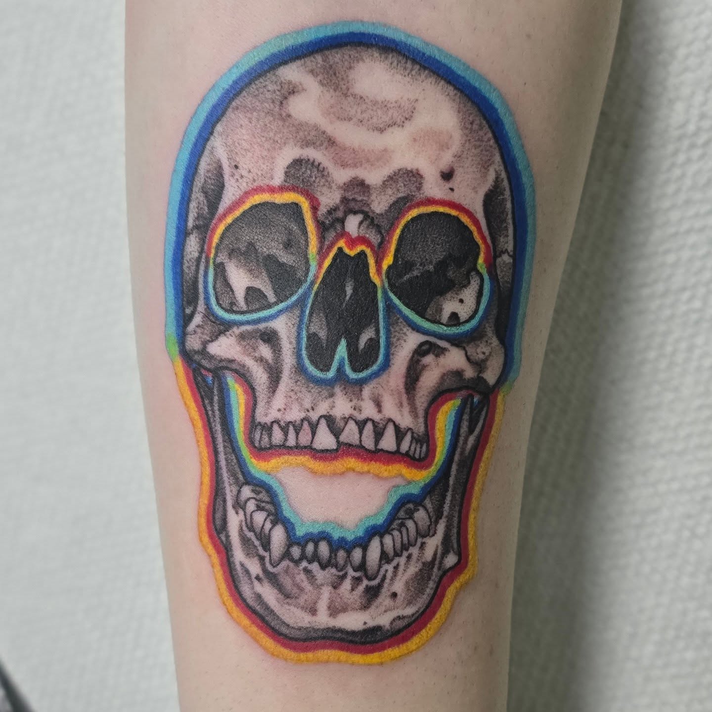 Skull with rainbow outline realism tattoo on the forearm by Lizz Zonno, Naperville, Illinois