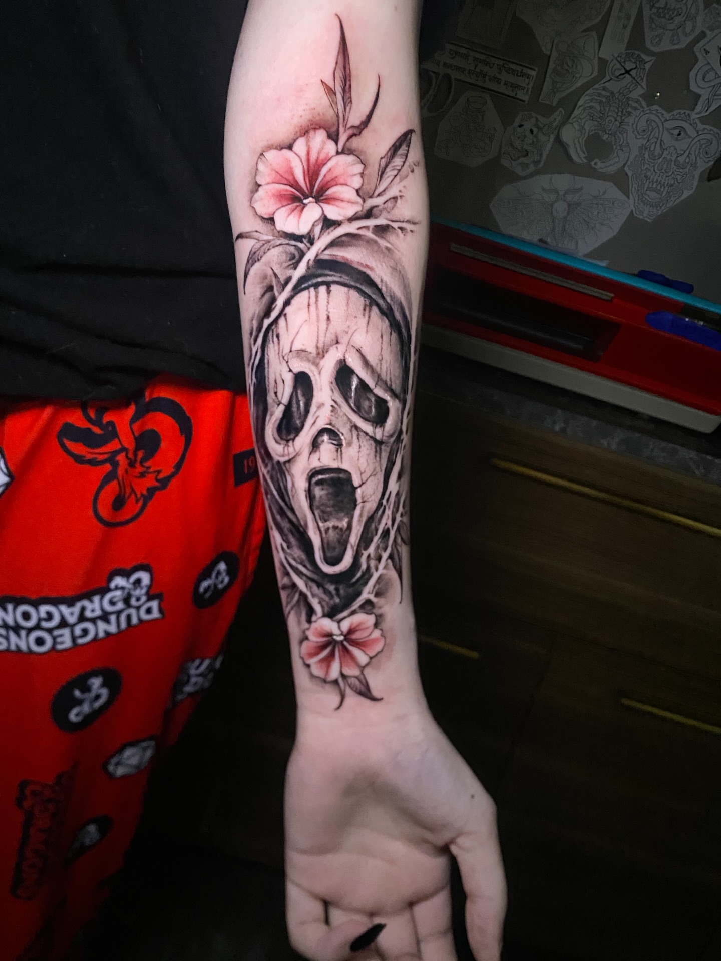 Scream skull with flowers realism tattoo on the forearm by Adam Newton