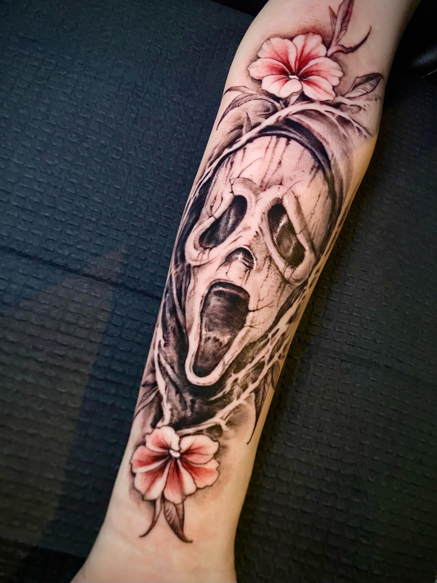 Skull with flowers realism tattoo on the forearm by Adam Newton