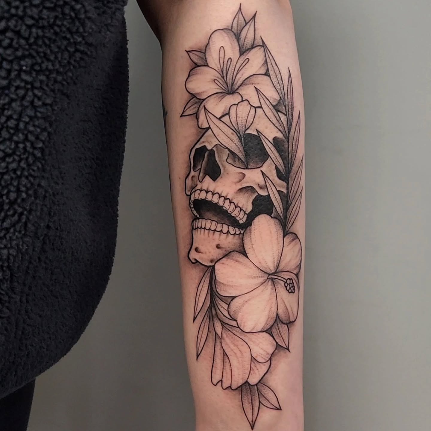 Skull with flowers realism tattoo on the forearm by Jason August