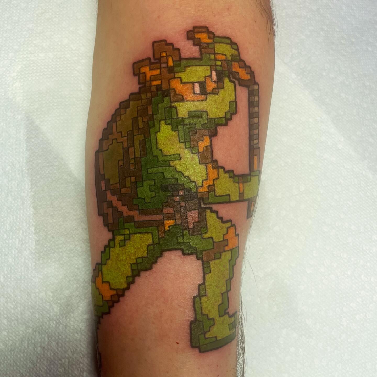 Pixel art character tattoo on the forearm by Robert Morrow