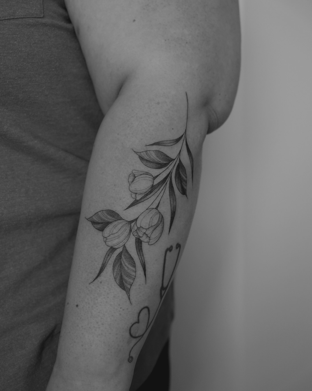 Tulips and leaves black and grey tattoo on the forearm by Haley Sayers