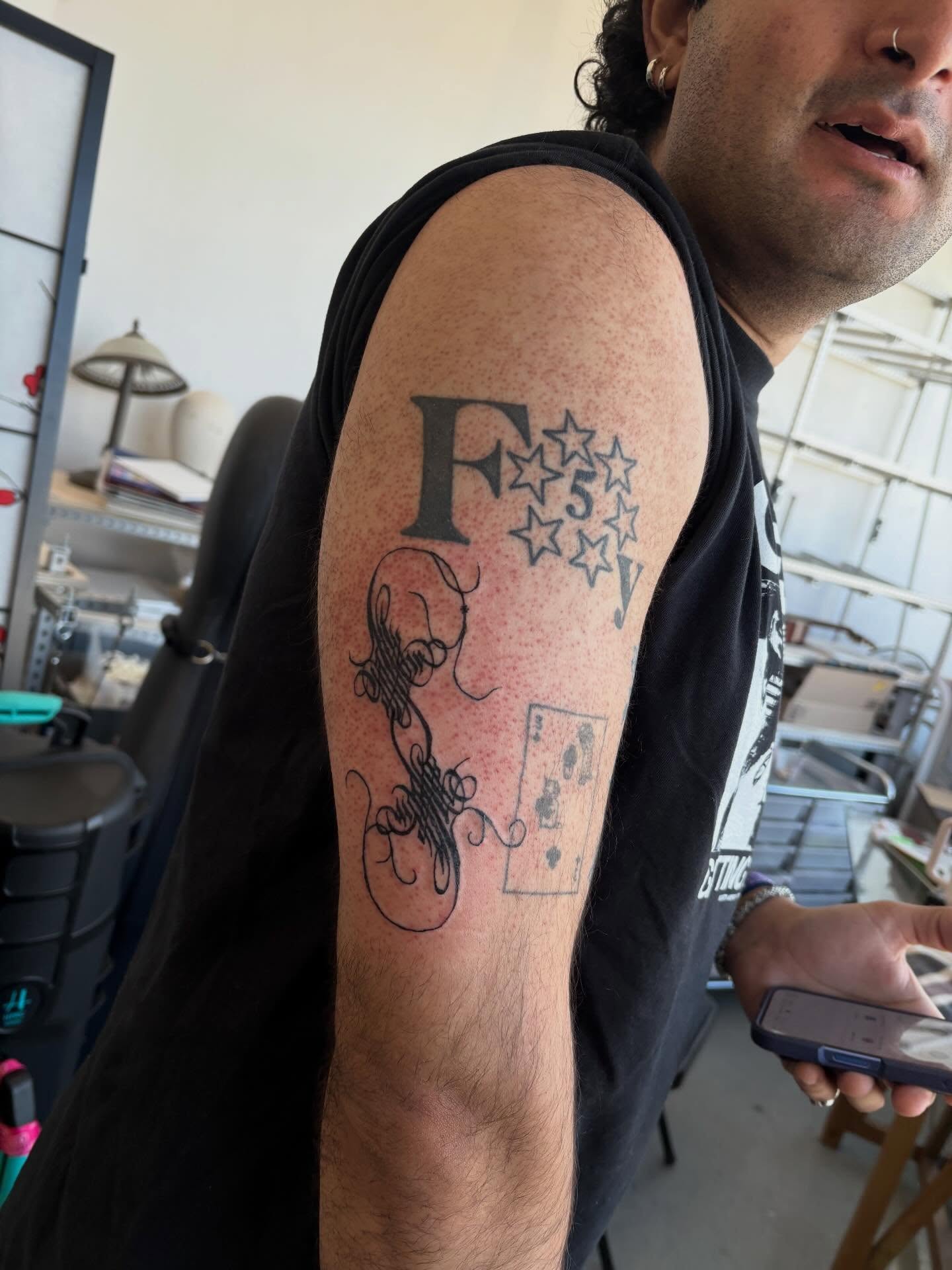 F with stars and decorative elements black and grey tattoo on the forearm by madeline