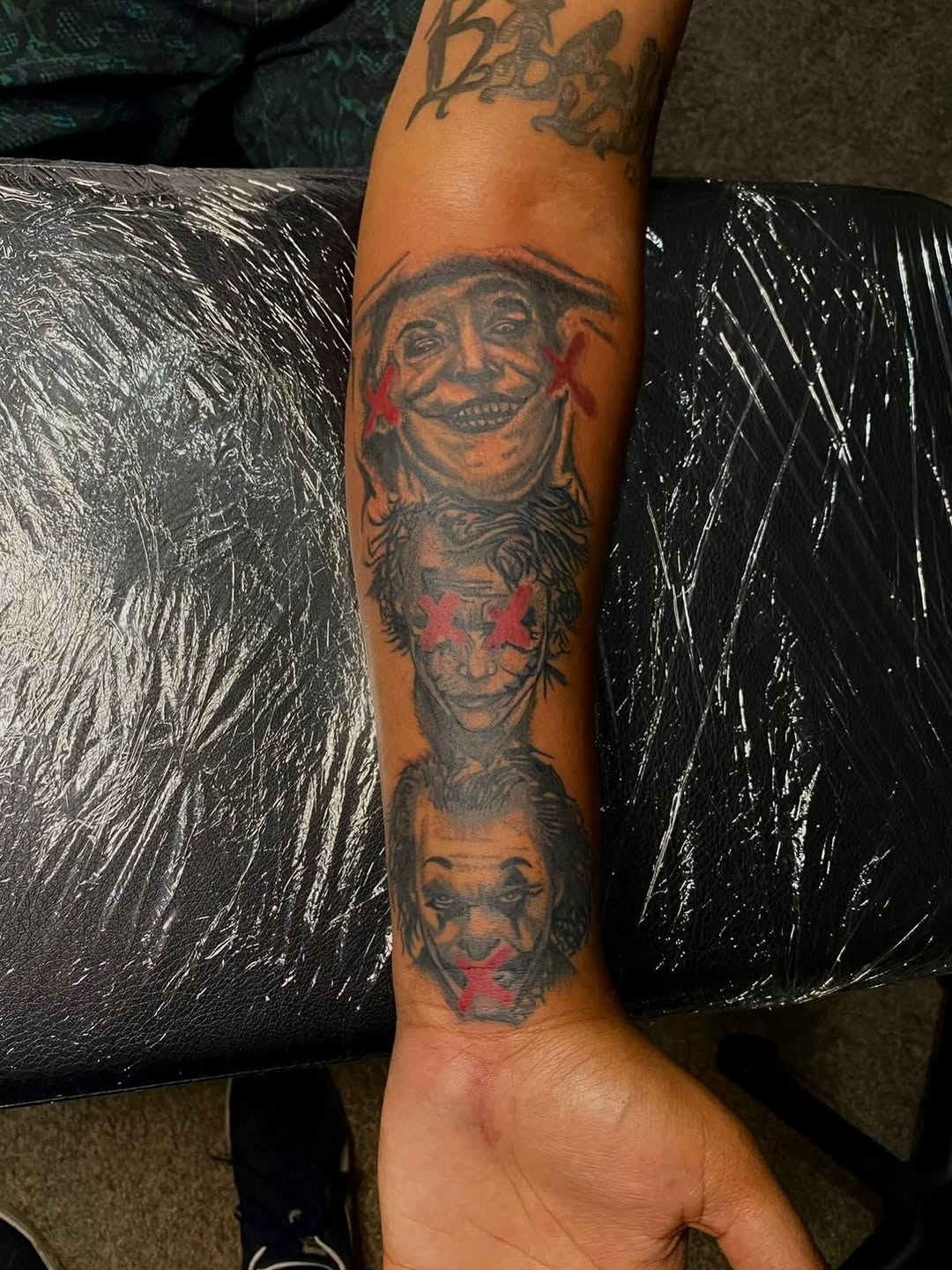 Three joker faces realism tattoo on the forearm by Jelani