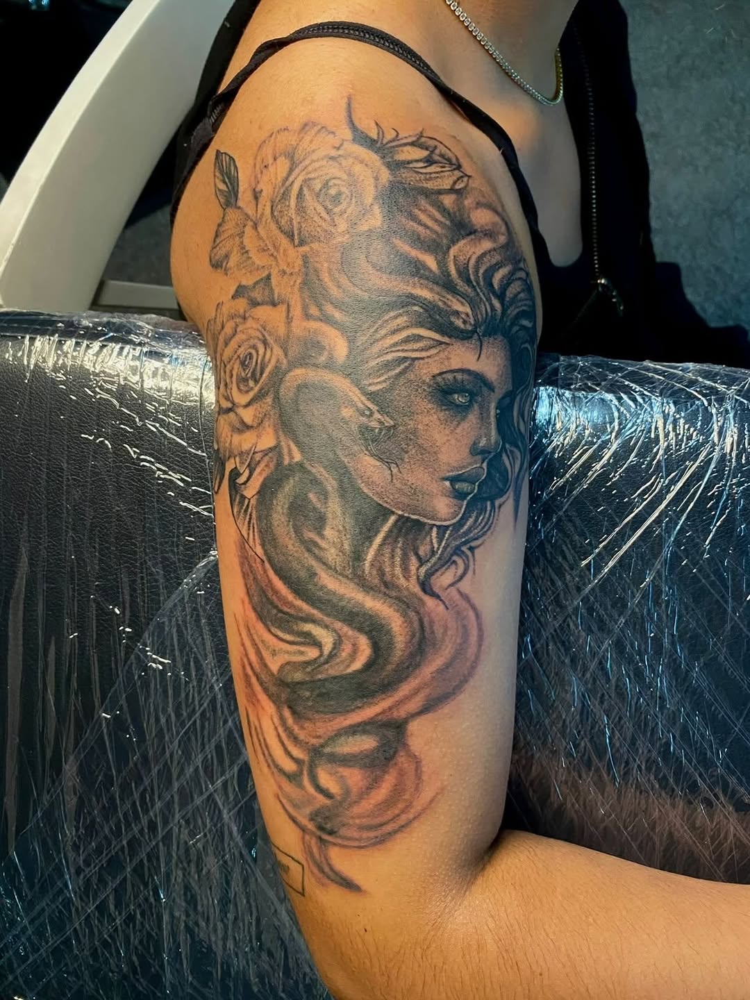 Woman with snake and roses realism tattoo on the upper arm by Jelani