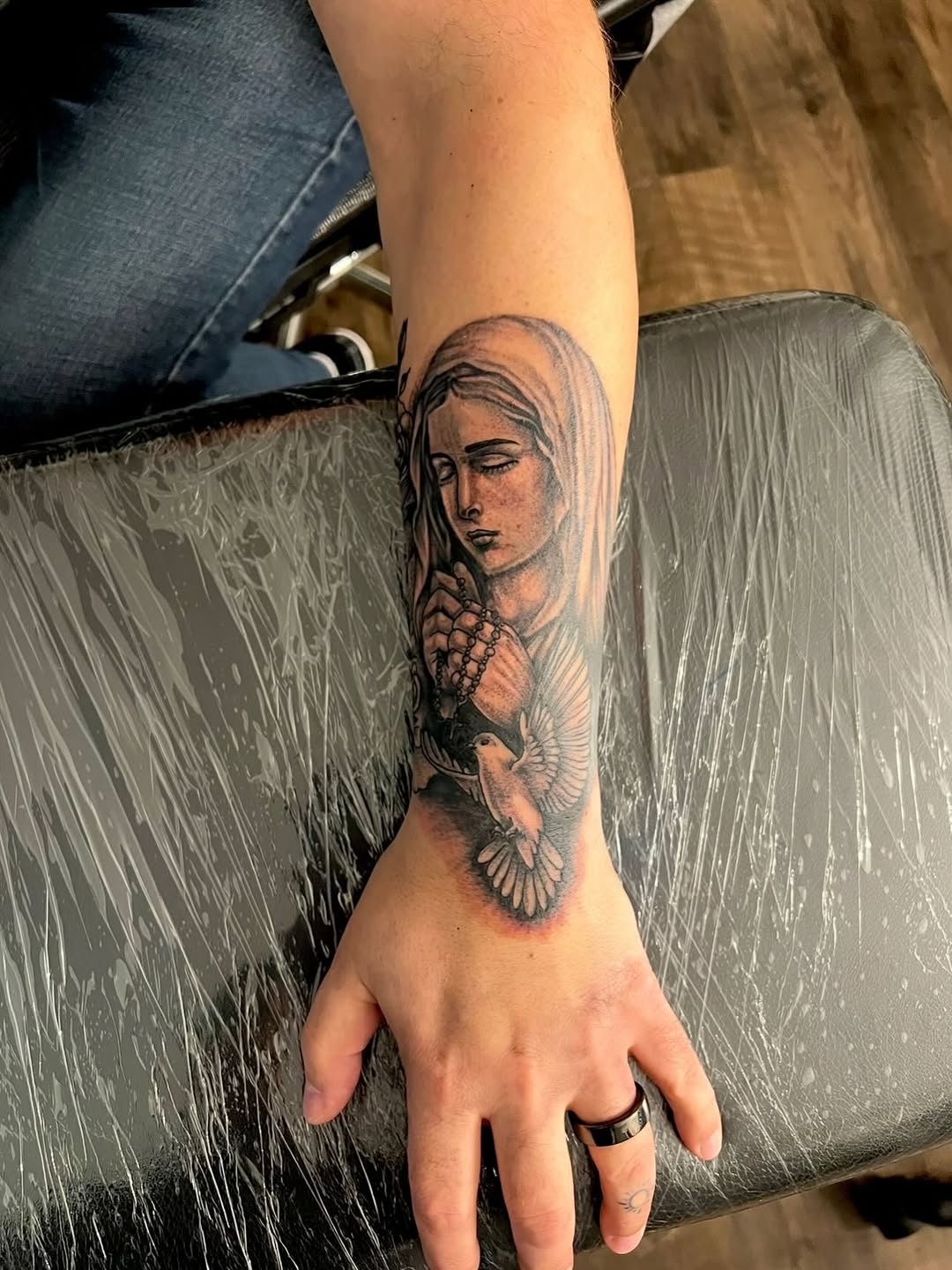 Virgin Mary with dove and rosary Chicano tattoo on the forearm by Jelani
