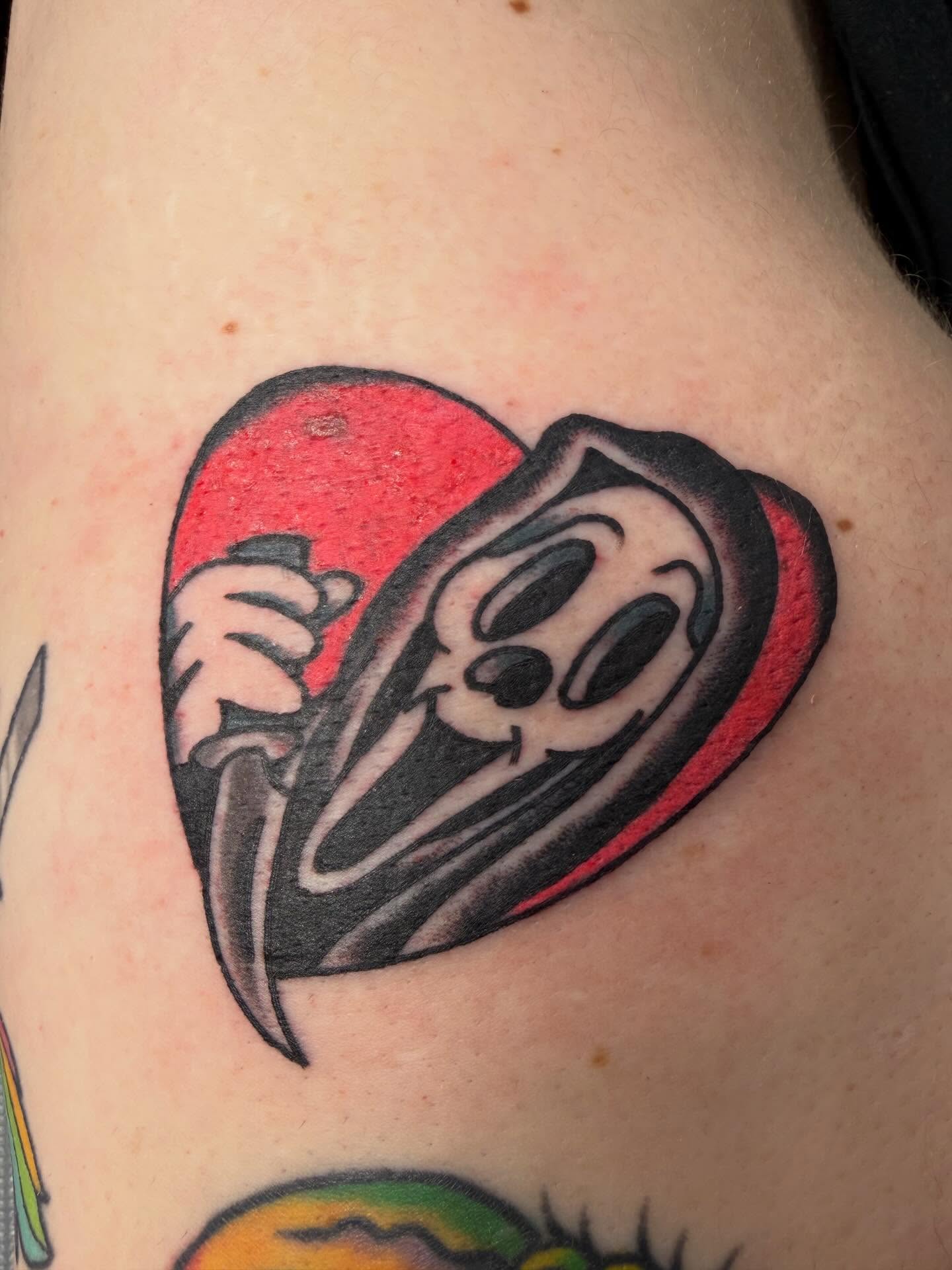 Heart with ghost American traditional tattoo on the upper arm by April Morris ⚔️ Tattoo Goblin
