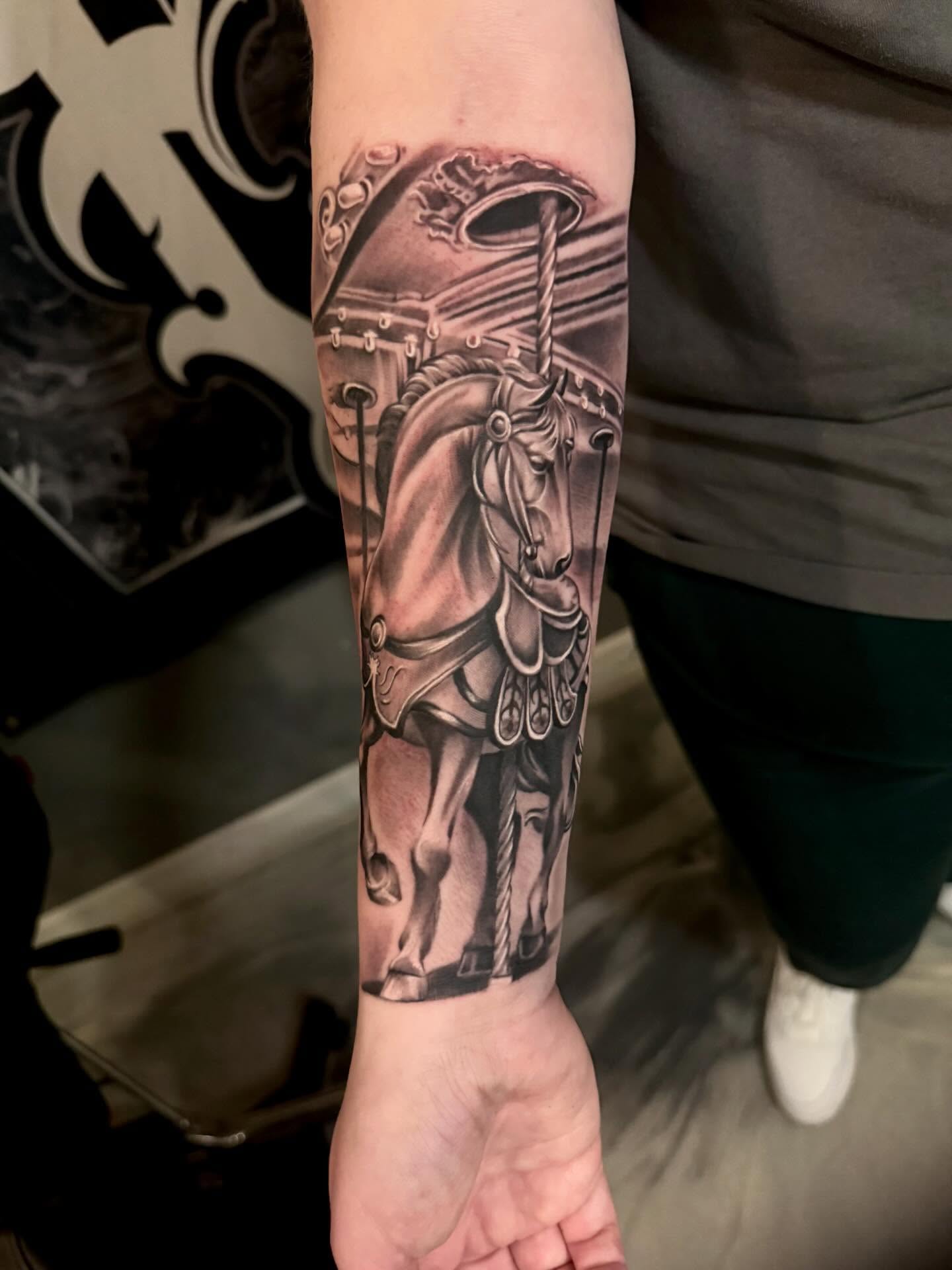 Horse and carousel realism tattoo on the forearm by Cody Pappas