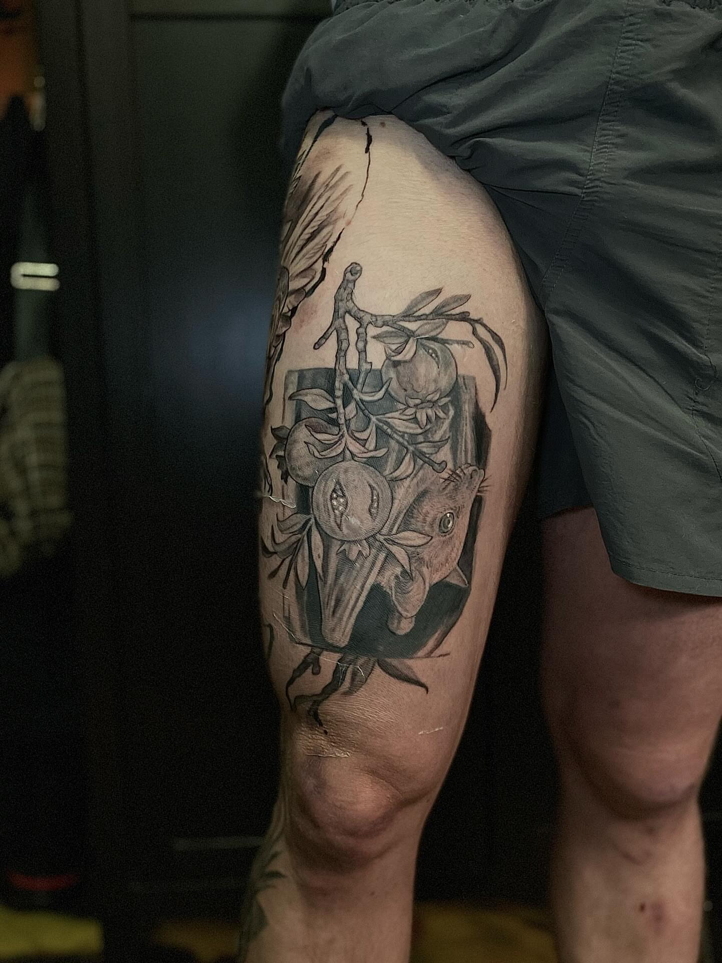 Mask and fruit realism tattoo on the thigh by Dana Jones