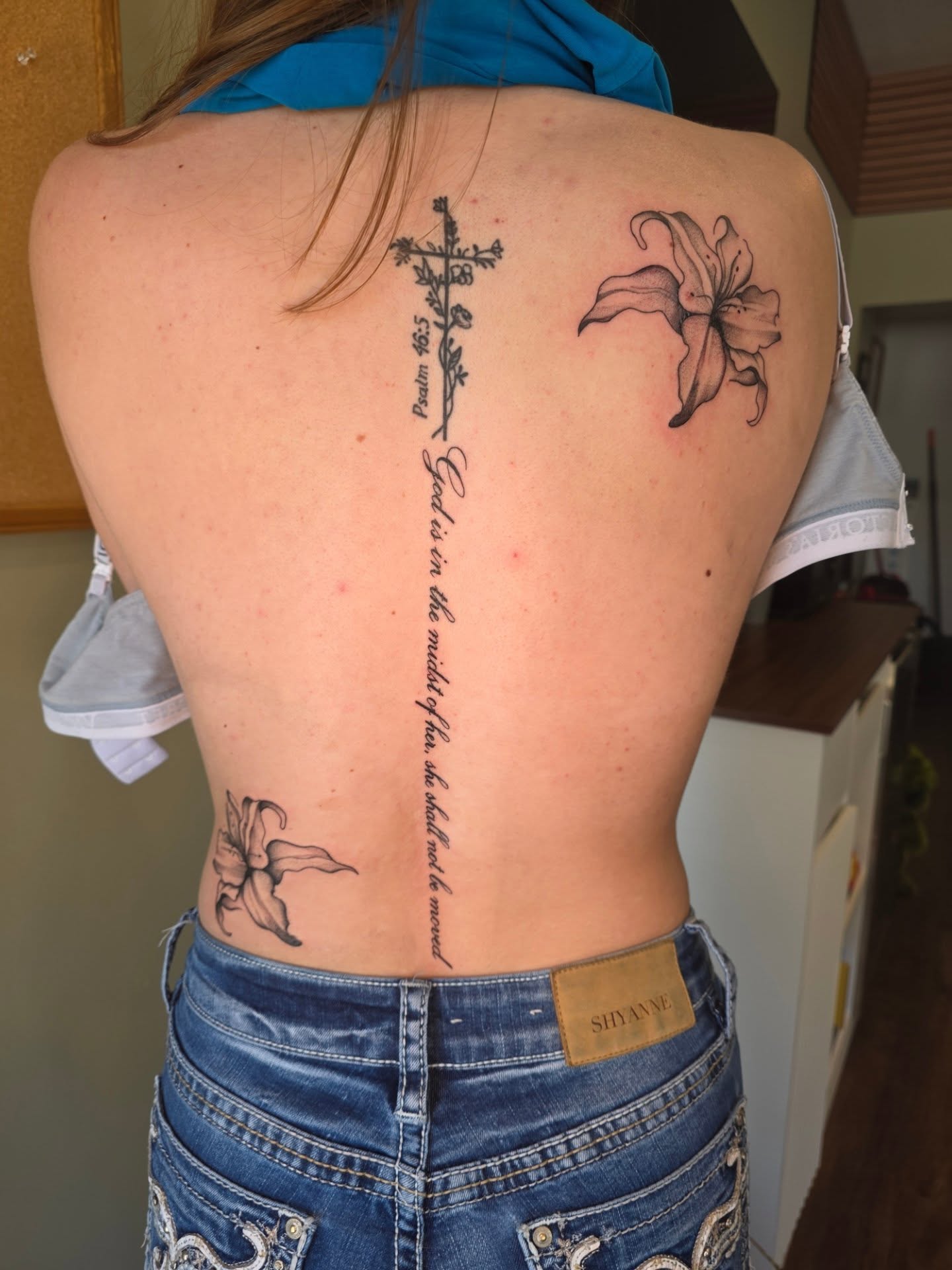 Cross and lily black and grey tattoo on the back by Maggie