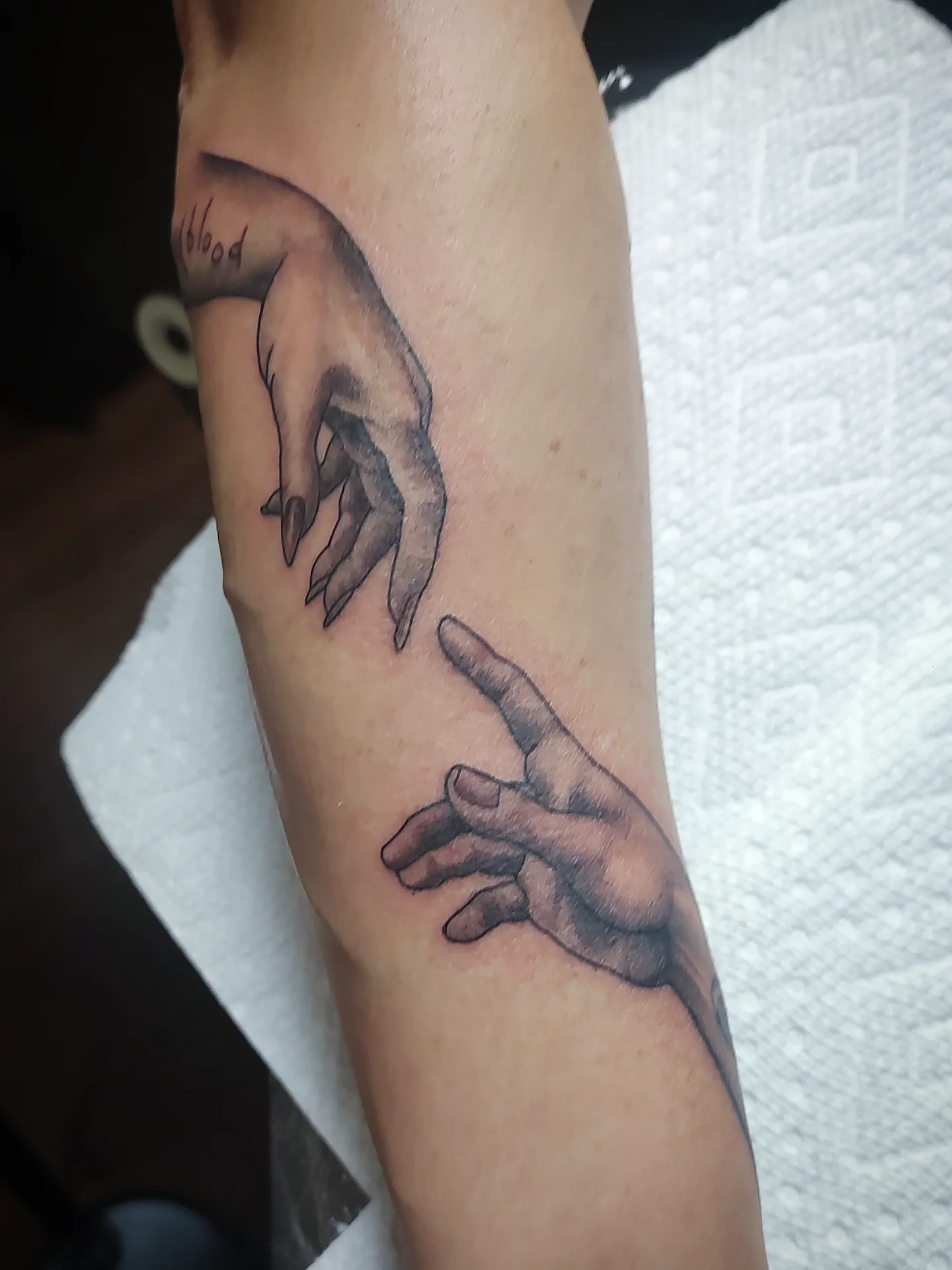 Hands reaching black and grey tattoo on the forearm by Jennifer Fowler