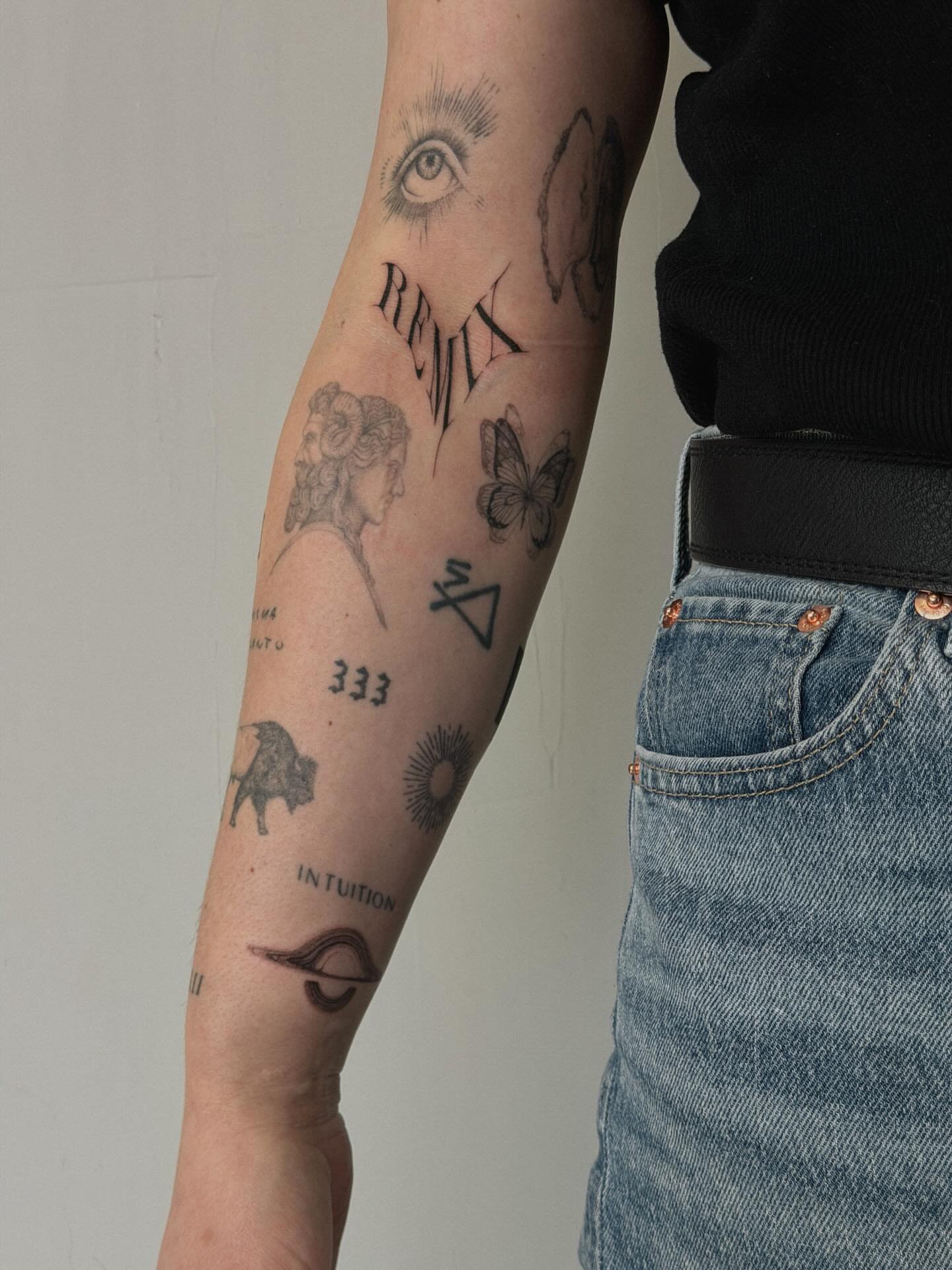 Eye, butterfly, woman's head, numbers, symbols black and grey tattoo on the forearm by Hannah Matthews